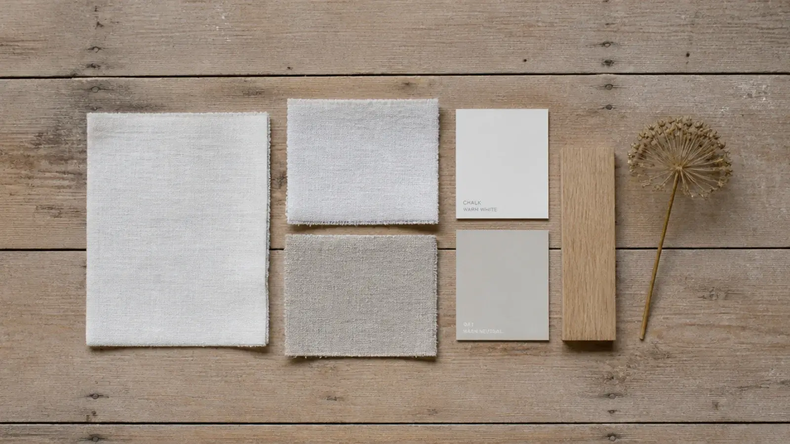 flatlay of linen swatches paint chips and a dried stem on attic boards