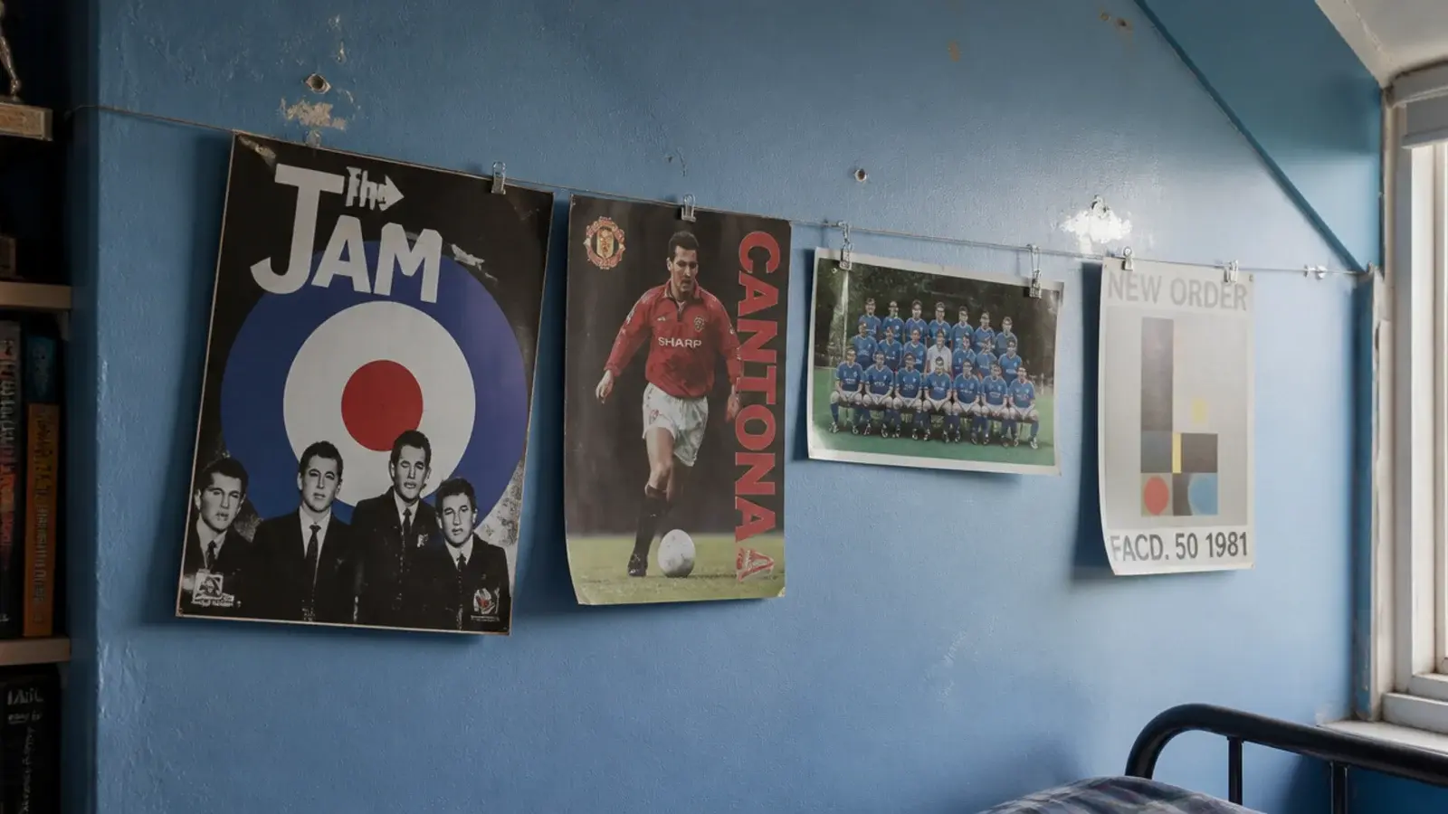 posters clipped to a wire strung across a boys attic bedroom wall