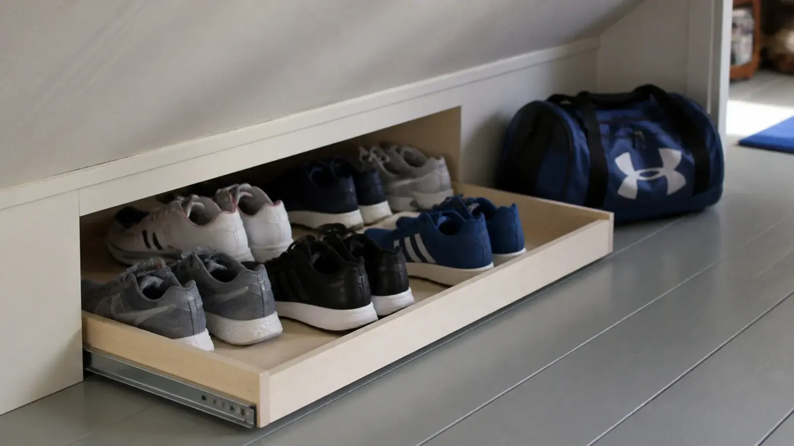 shallow pull out tray of trainers stored under an attic eaves slope