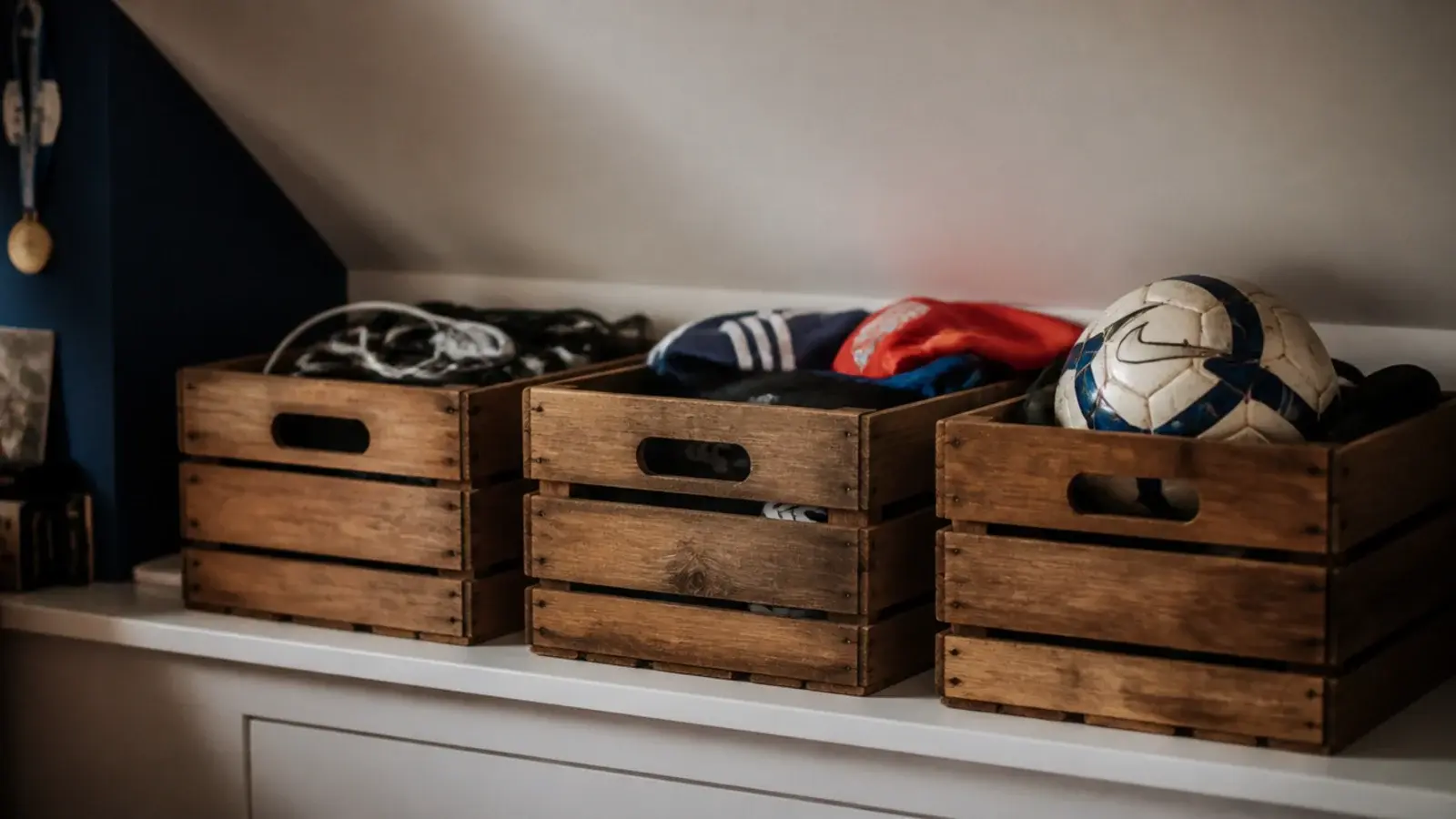 wooden crates lined along an attic knee wall shelf holding gear
