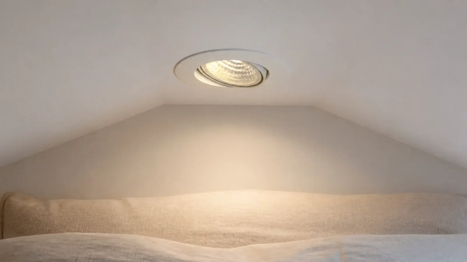 recessed downlight fitted flush into a sloping attic ceiling with angled trim