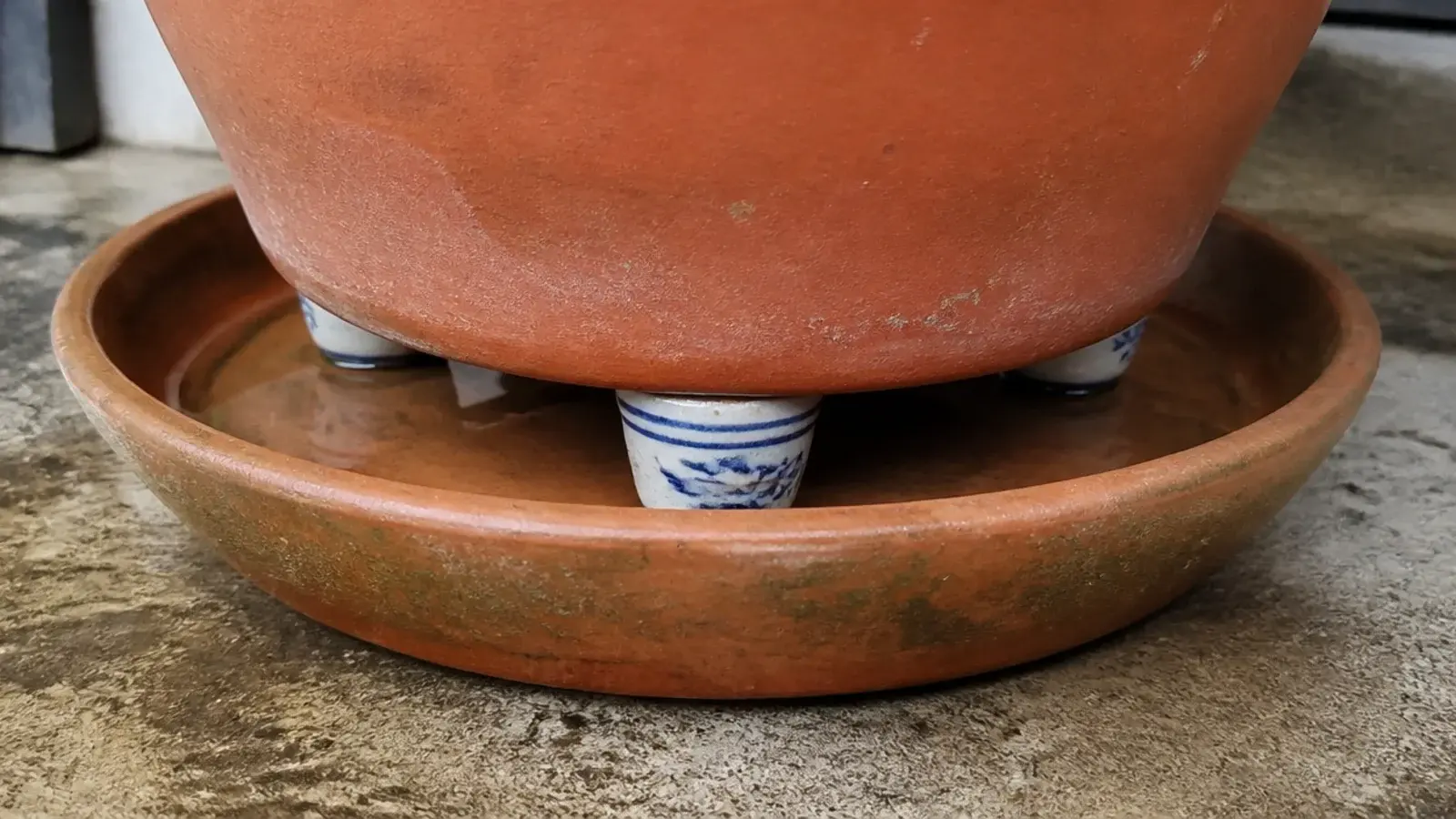 clay pot raised on small feet above a saucer of standing water