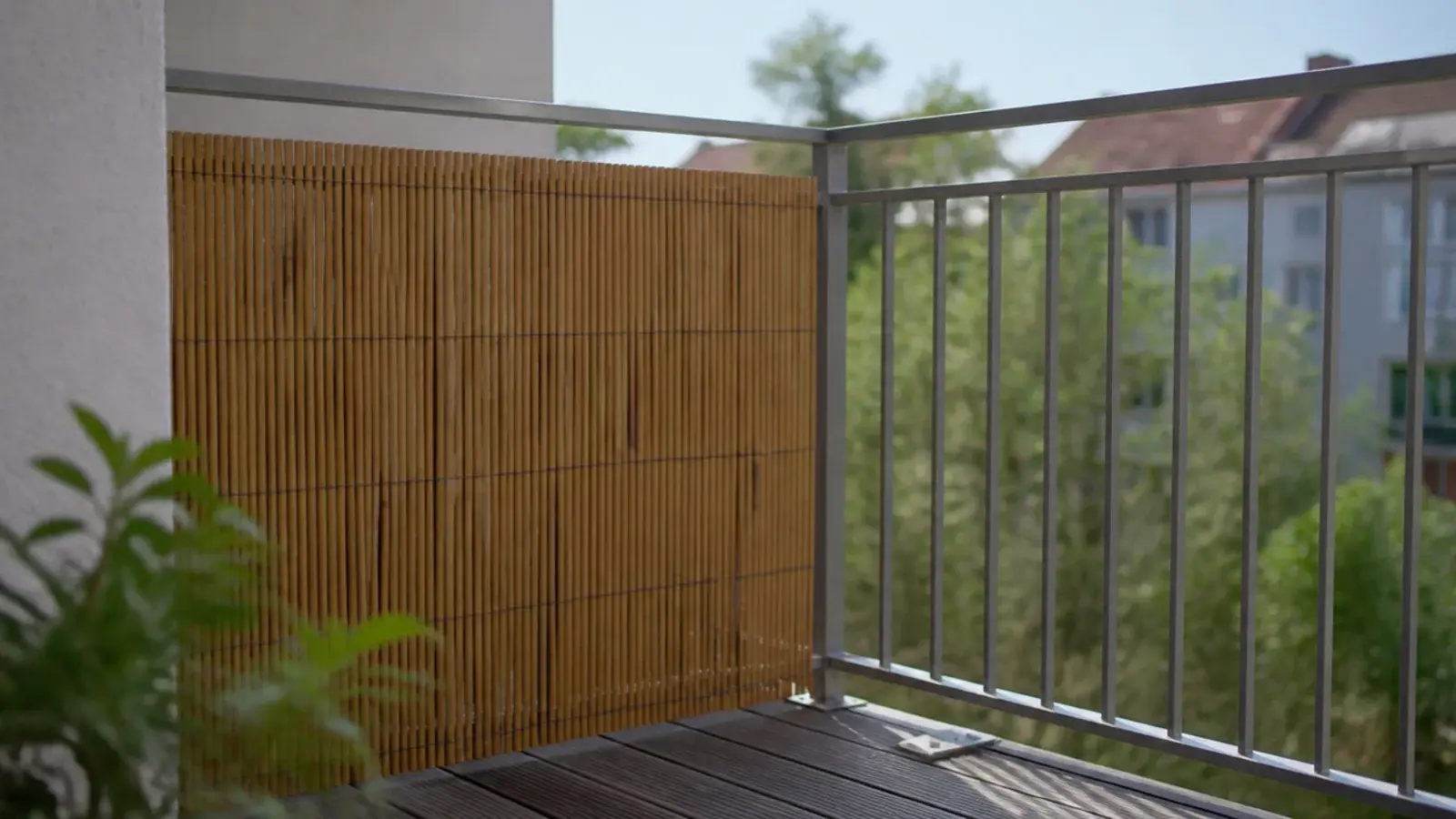 reed screen panel fixed inside one corner of an apartment balcony rail
