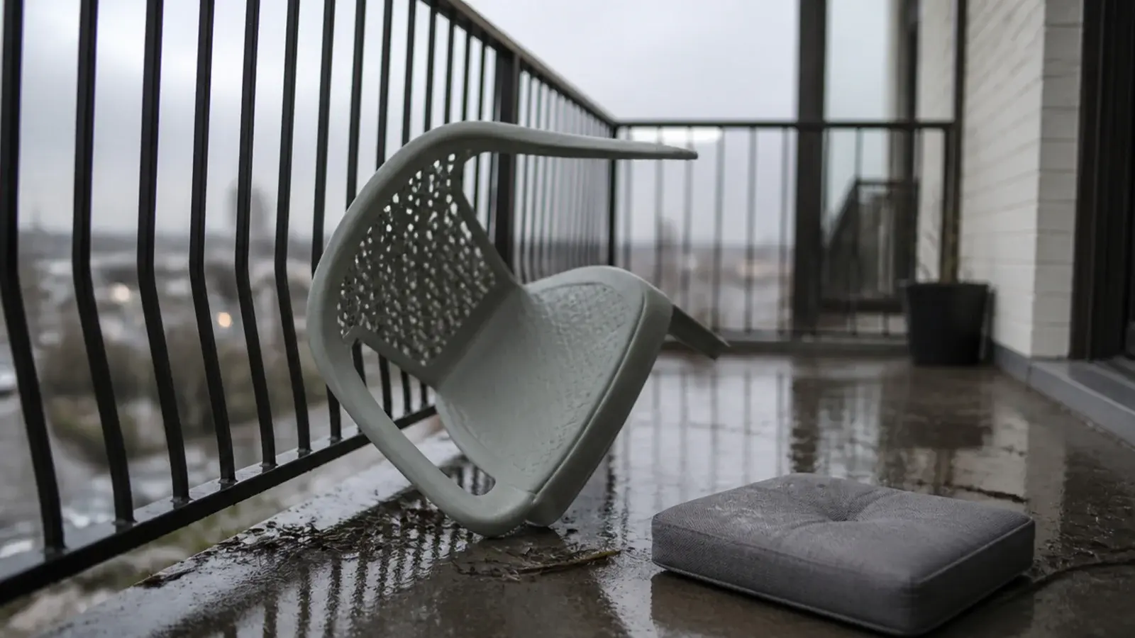 hollow resin chair tipped over against a balcony railing after wind