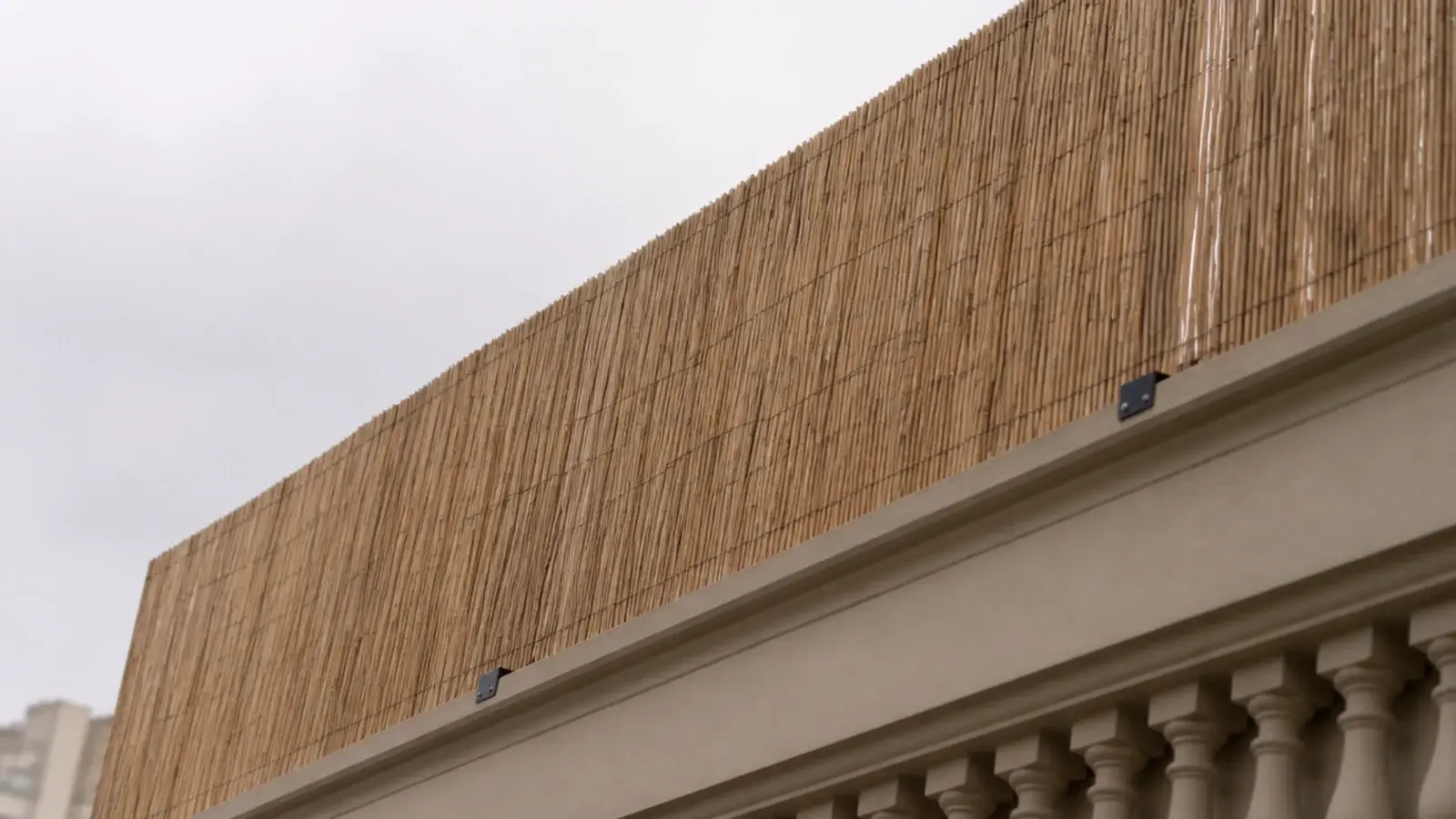 tall reed screen rising well above an apartment balcony railing