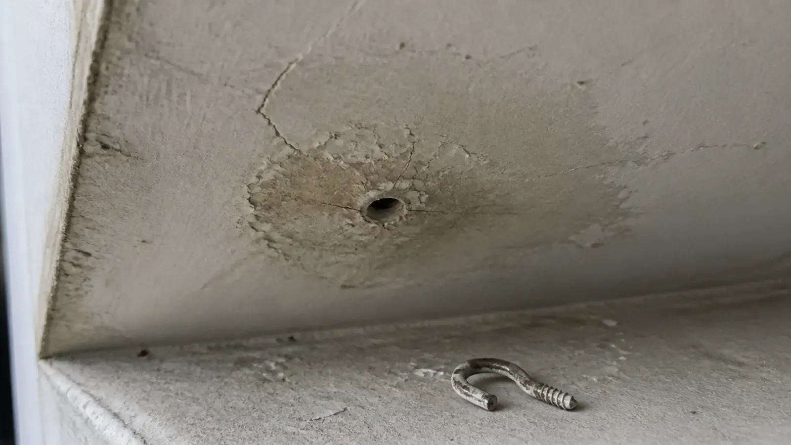 small drilled hole and cracked paint in a balcony ceiling soffit