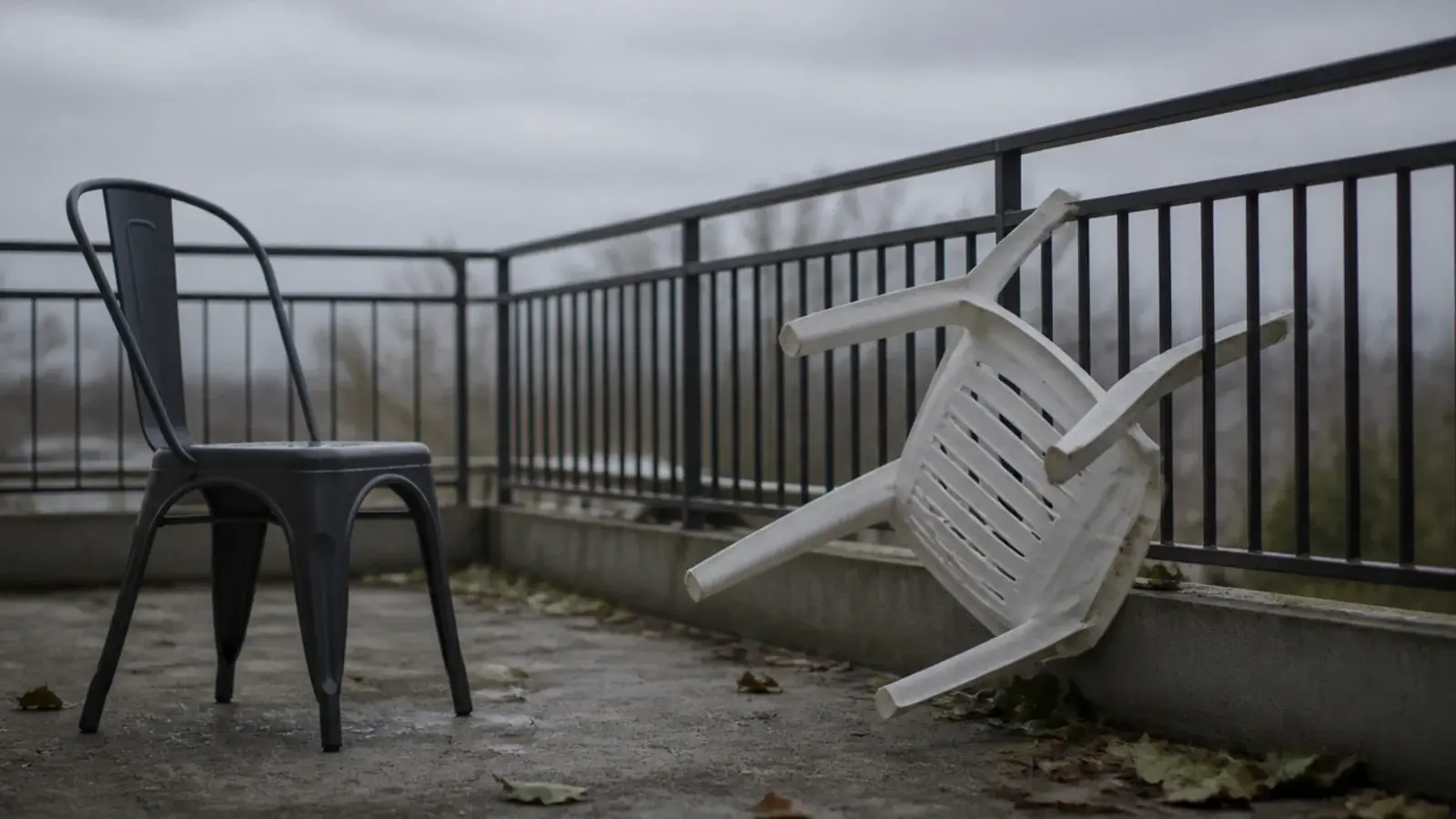 lightweight plastic chair blown against a balcony railing in wind