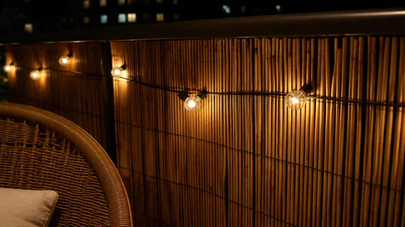 string lights threaded through reed screening on a balcony at night