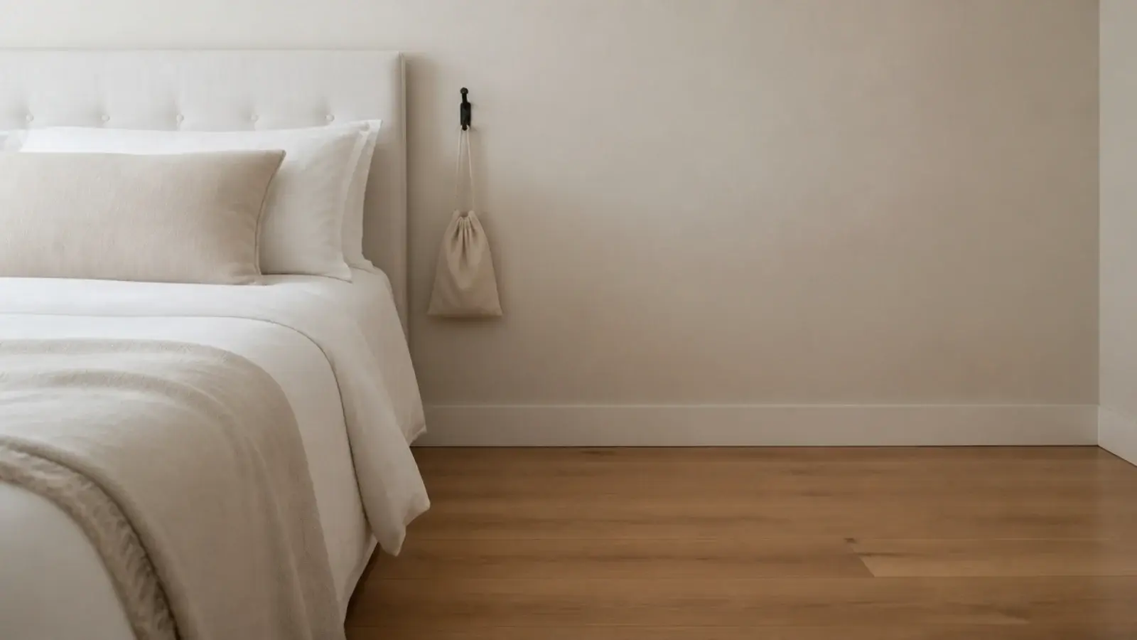 empty floor beside a bed with only a wall hook and small bag