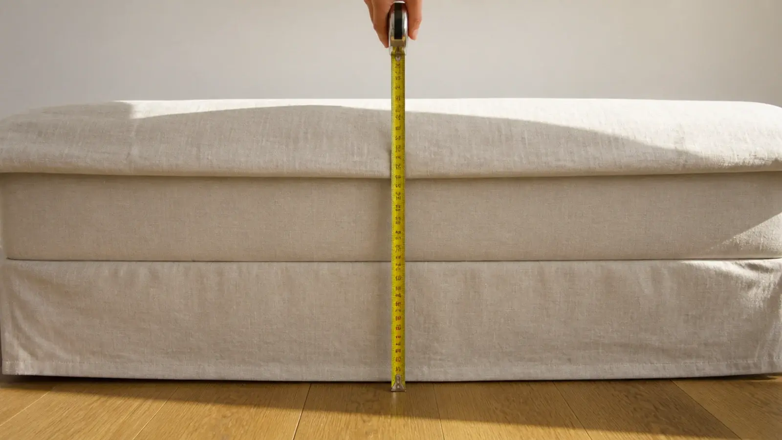 tape measure held from bedroom floor to the top of a mattress