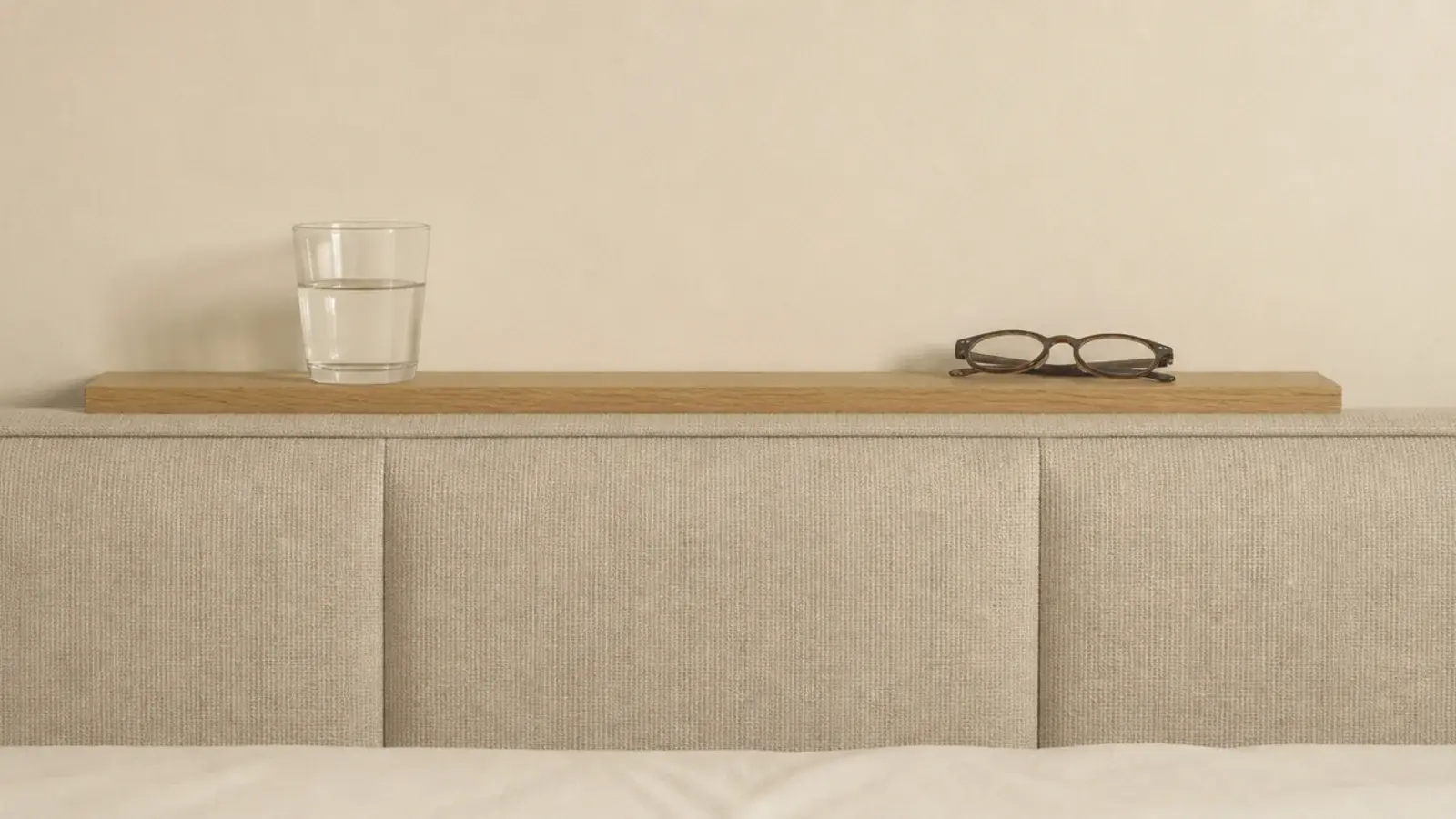 narrow ledge running behind a headboard holding a glass and phone