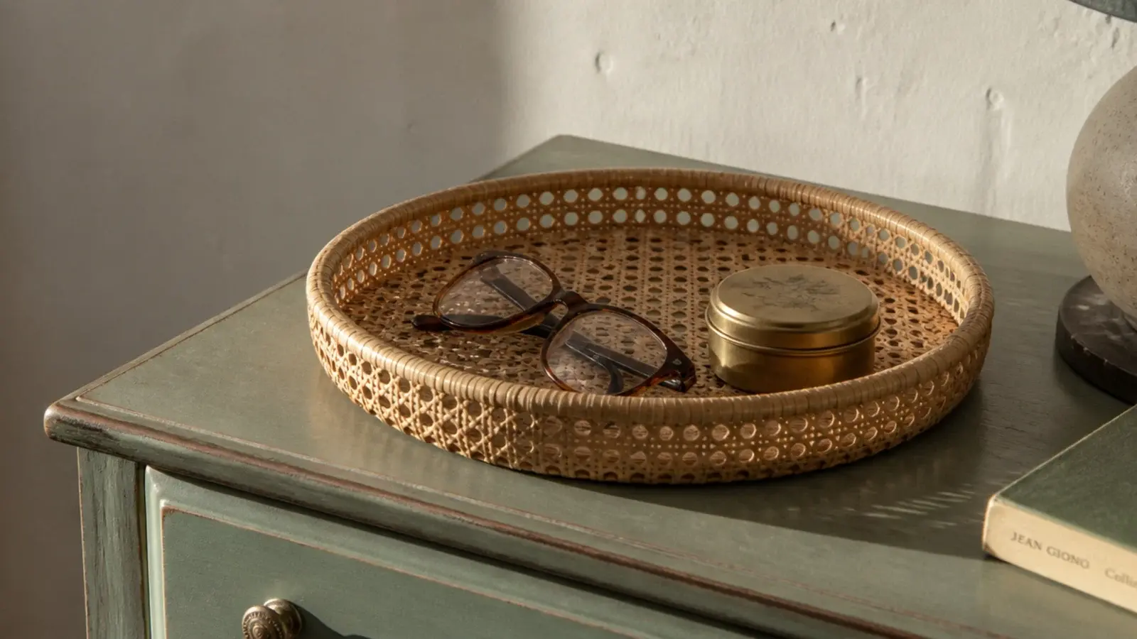 woven cane tray holding small objects on a bedside surface