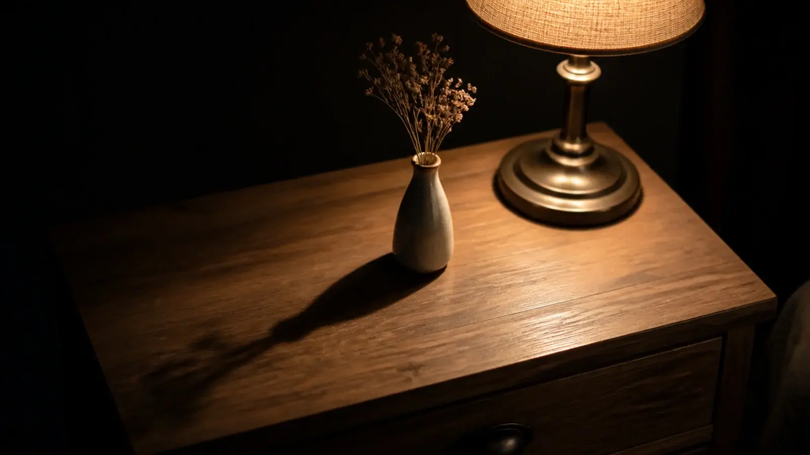 long soft shadow thrown across a nightstand by a single lamp