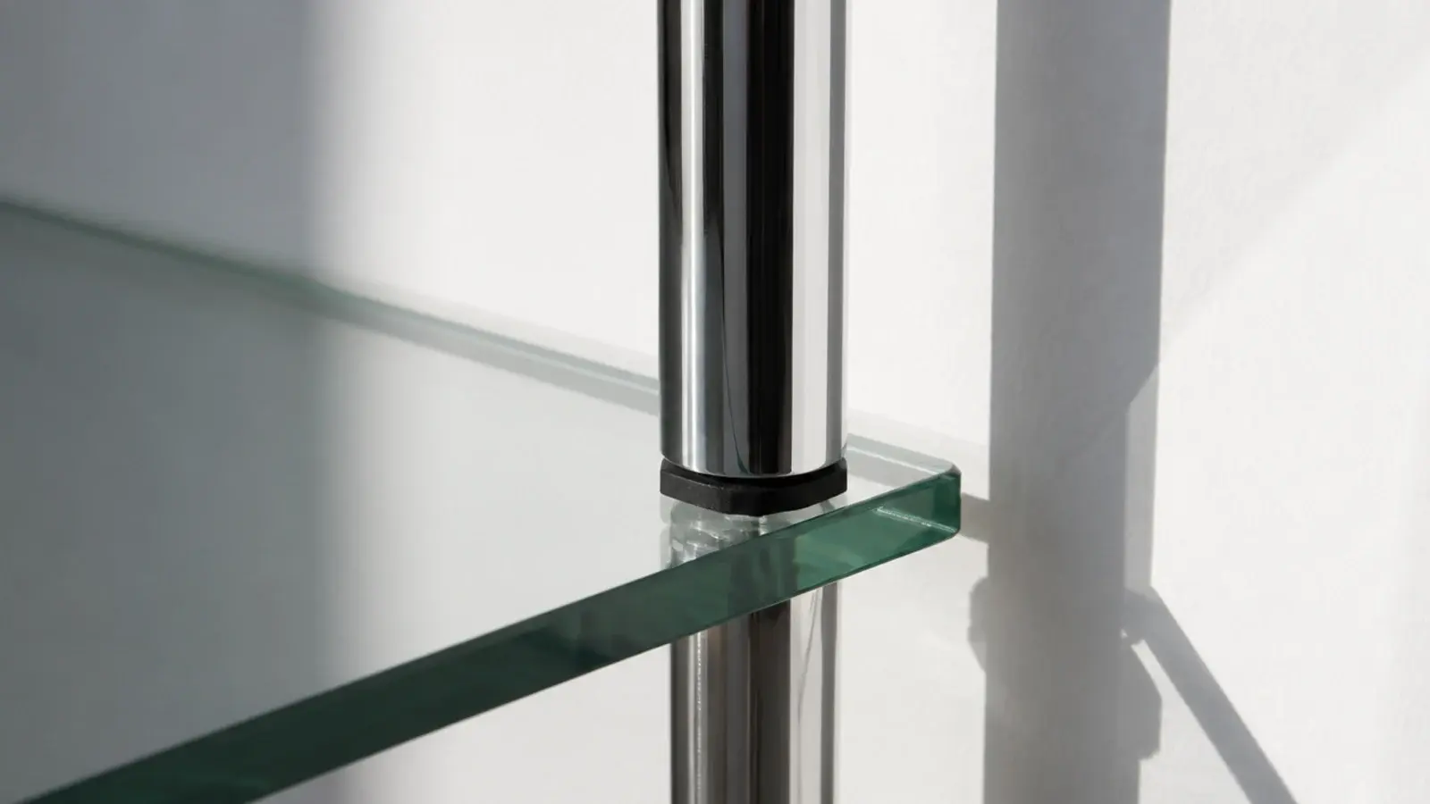 thin steel tube frame supporting a clear glass bedside shelf
