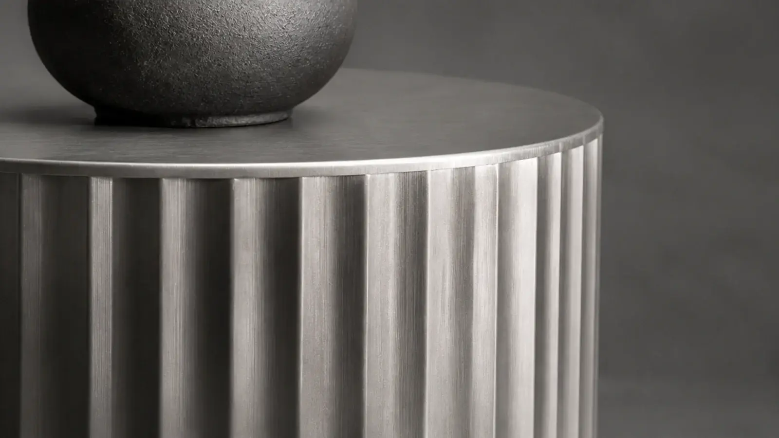 ribbed corrugated aluminium drum table catching light around its curve