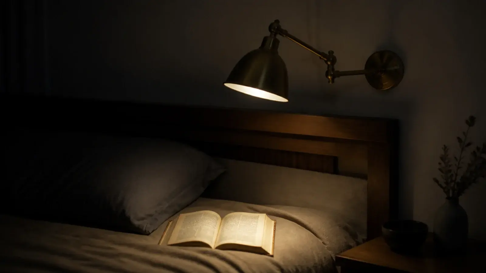 brass swing arm sconce angled down over a pillow and open book