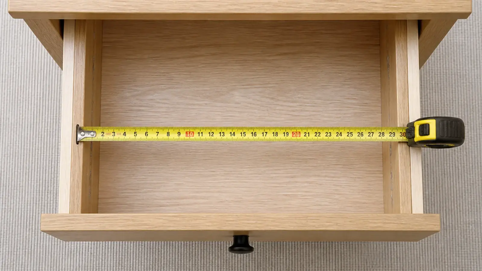 tape measure held across the inside width of an open bedside drawer