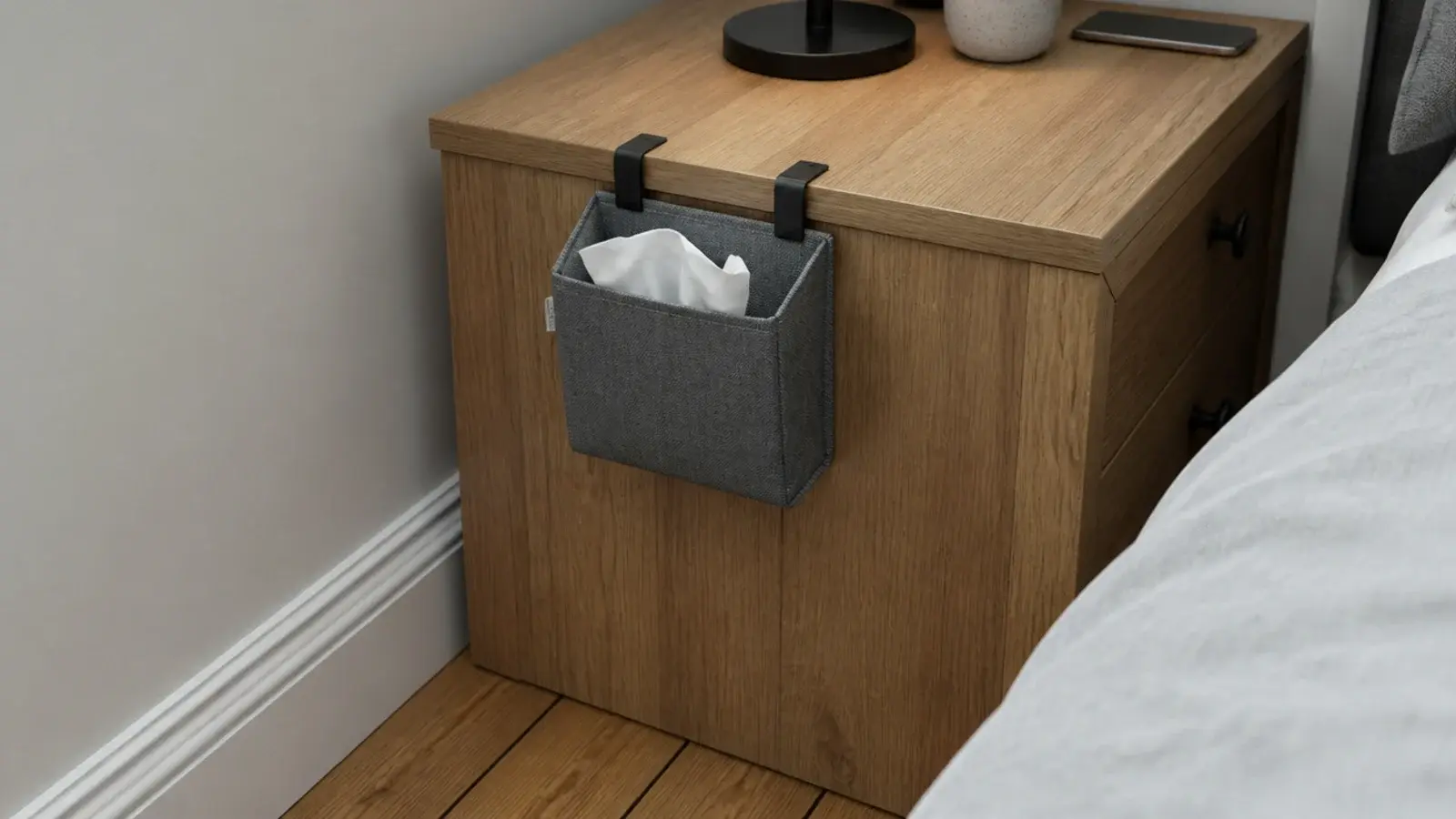 small fabric waste pouch clipped to the back of a bedside cabinet