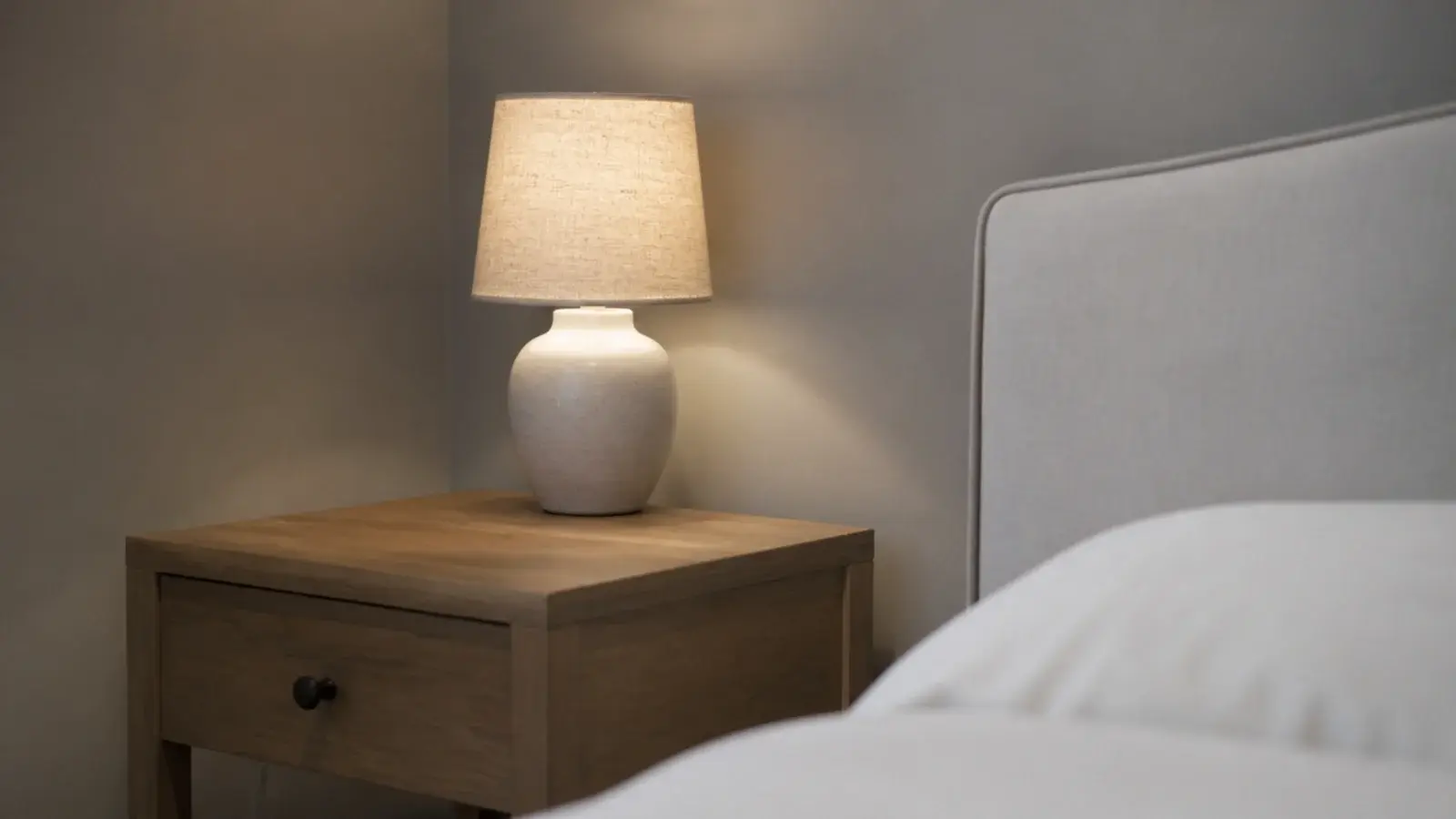 lamp positioned at the back corner of an otherwise empty bedside table