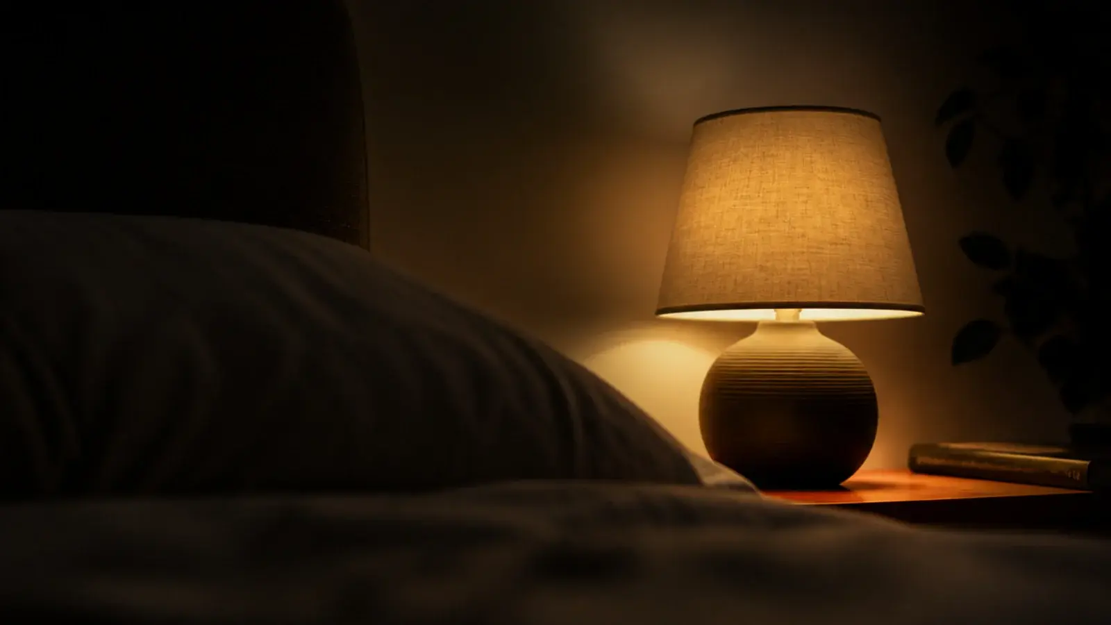 view from a pillow toward a lit bedside lamp and shaded bulb