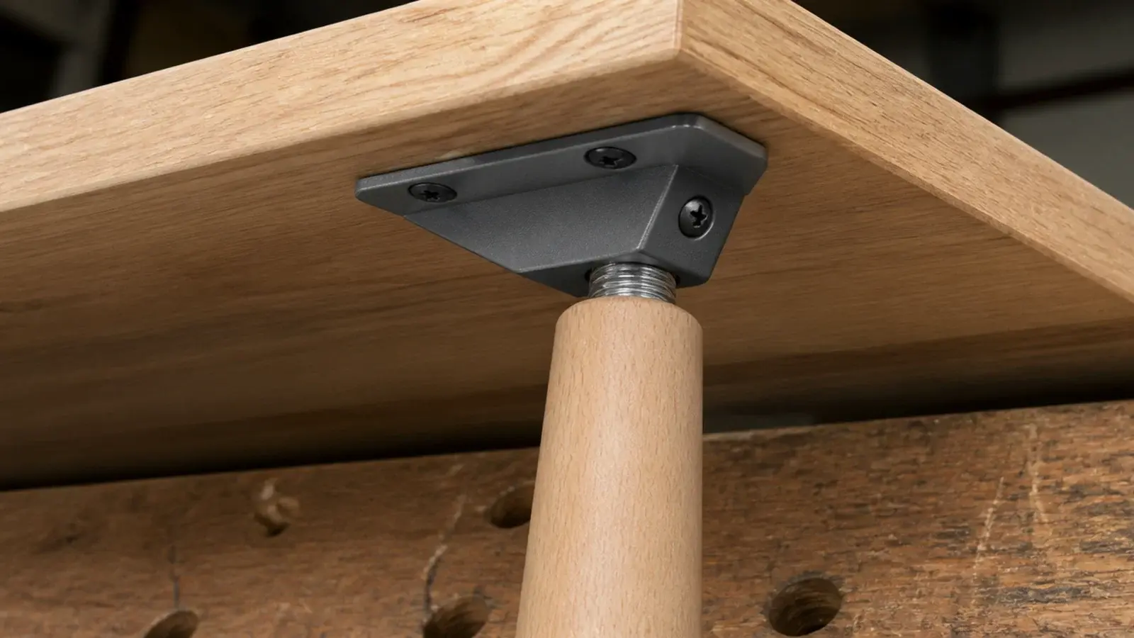 steel angle plate screwed under a tabletop holding a tapered leg
