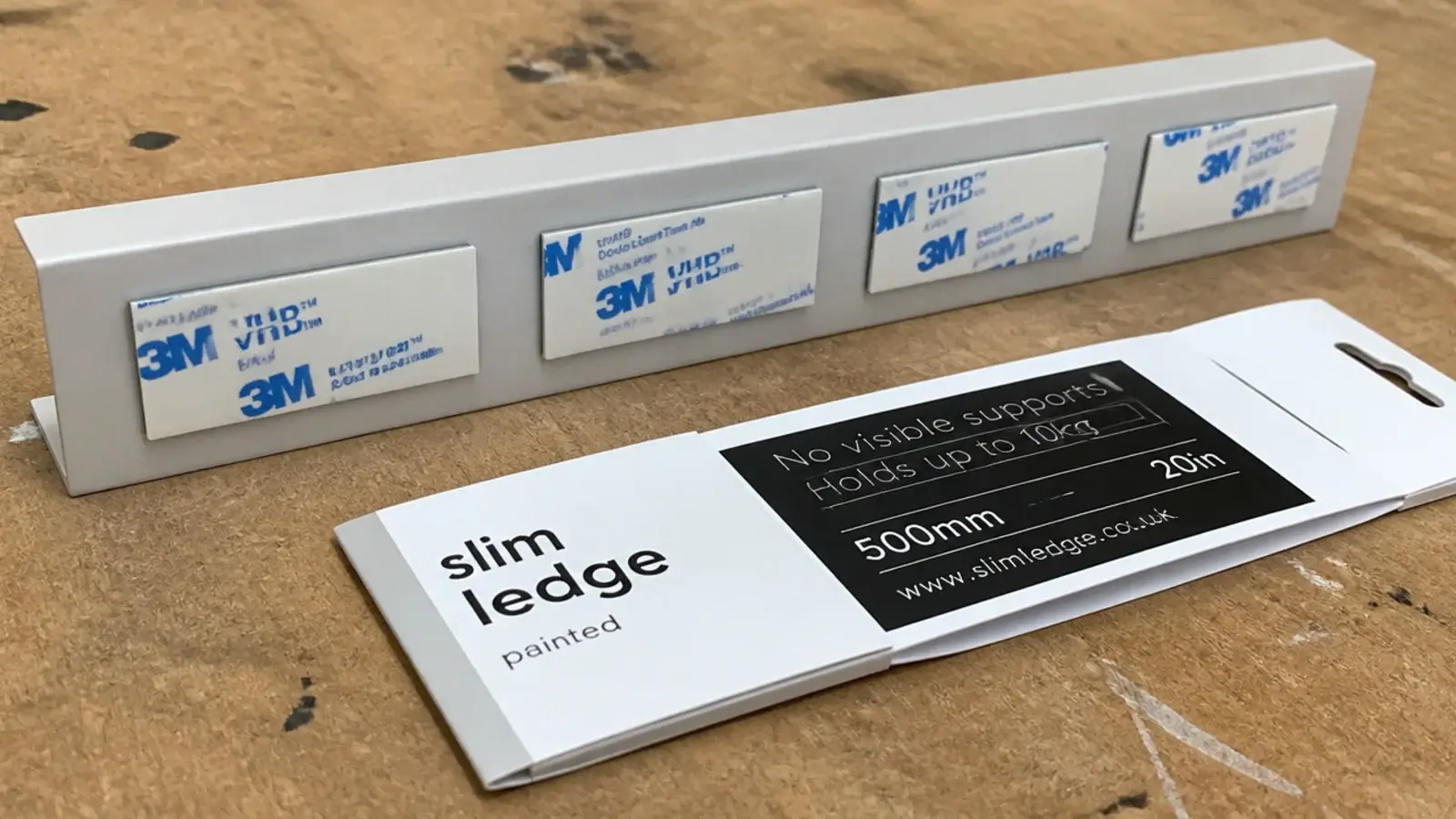 adhesive strips being pressed onto the back of a slim wall ledge