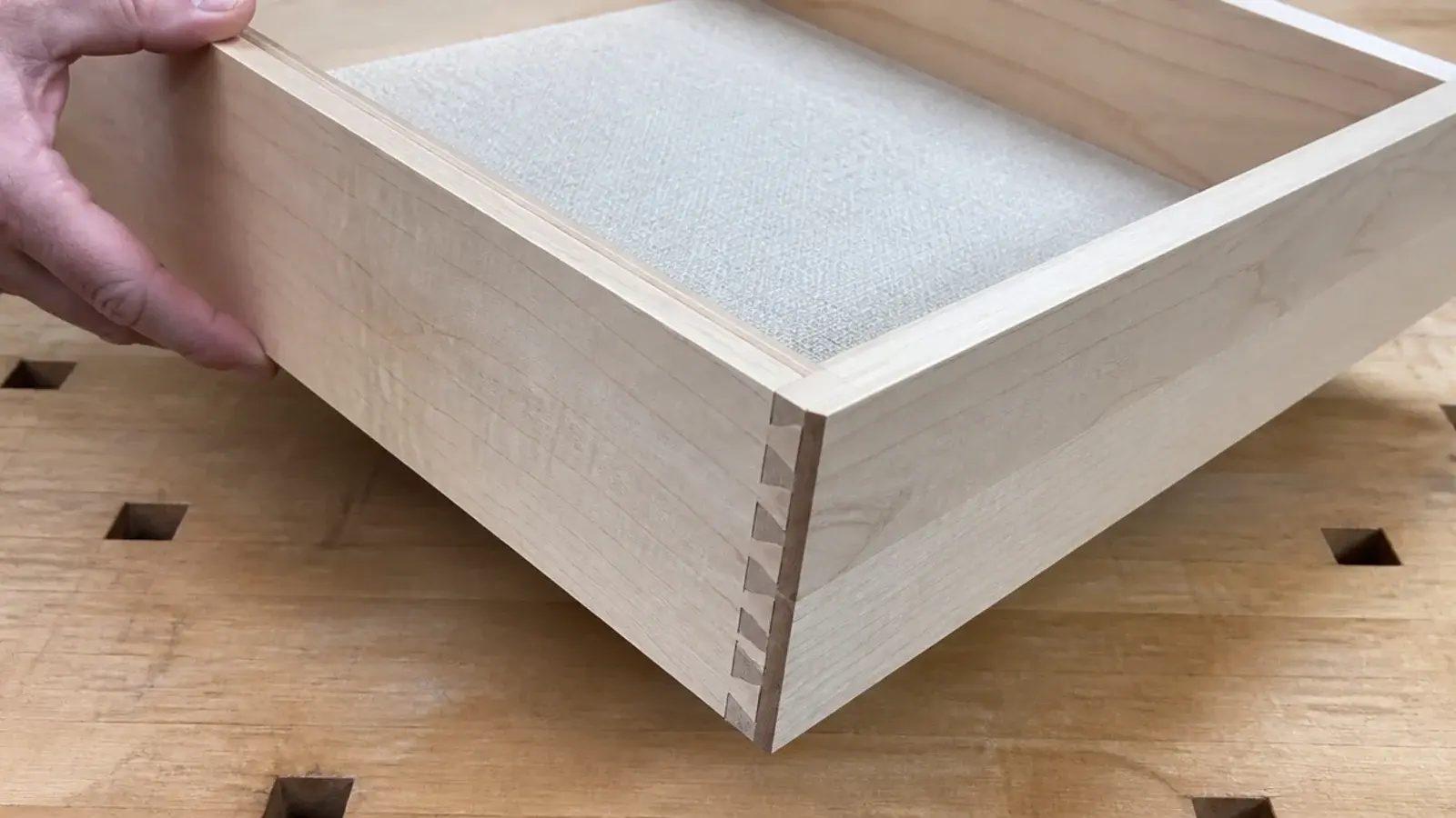 open drawer showing hand-cut dovetail joints in pale solid maple