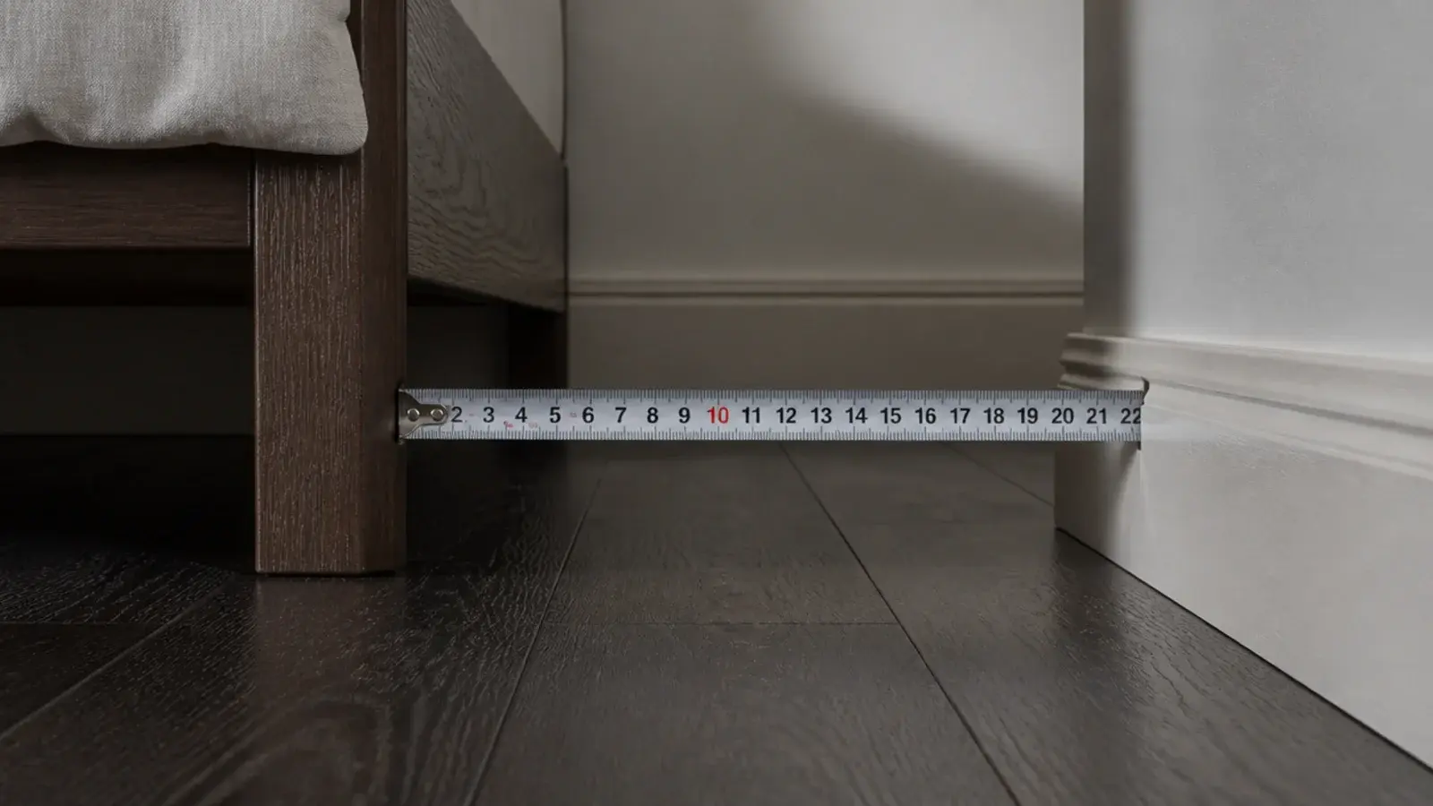 tape measure held across a slim gap at skirting board height