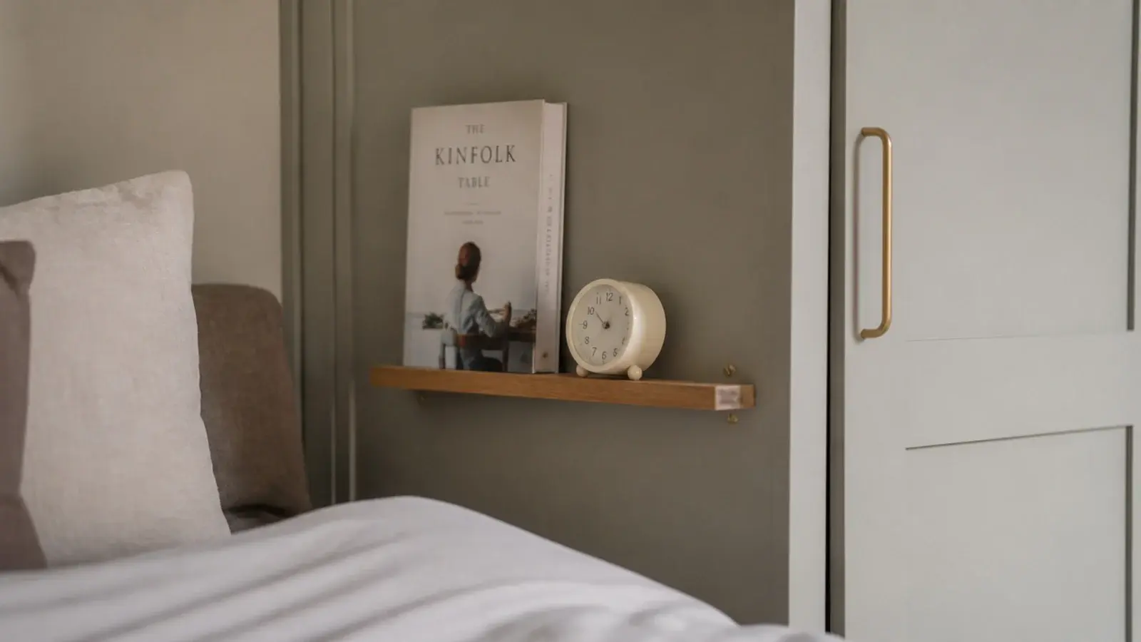 small shelf fixed to the side of a wardrobe next to a bed