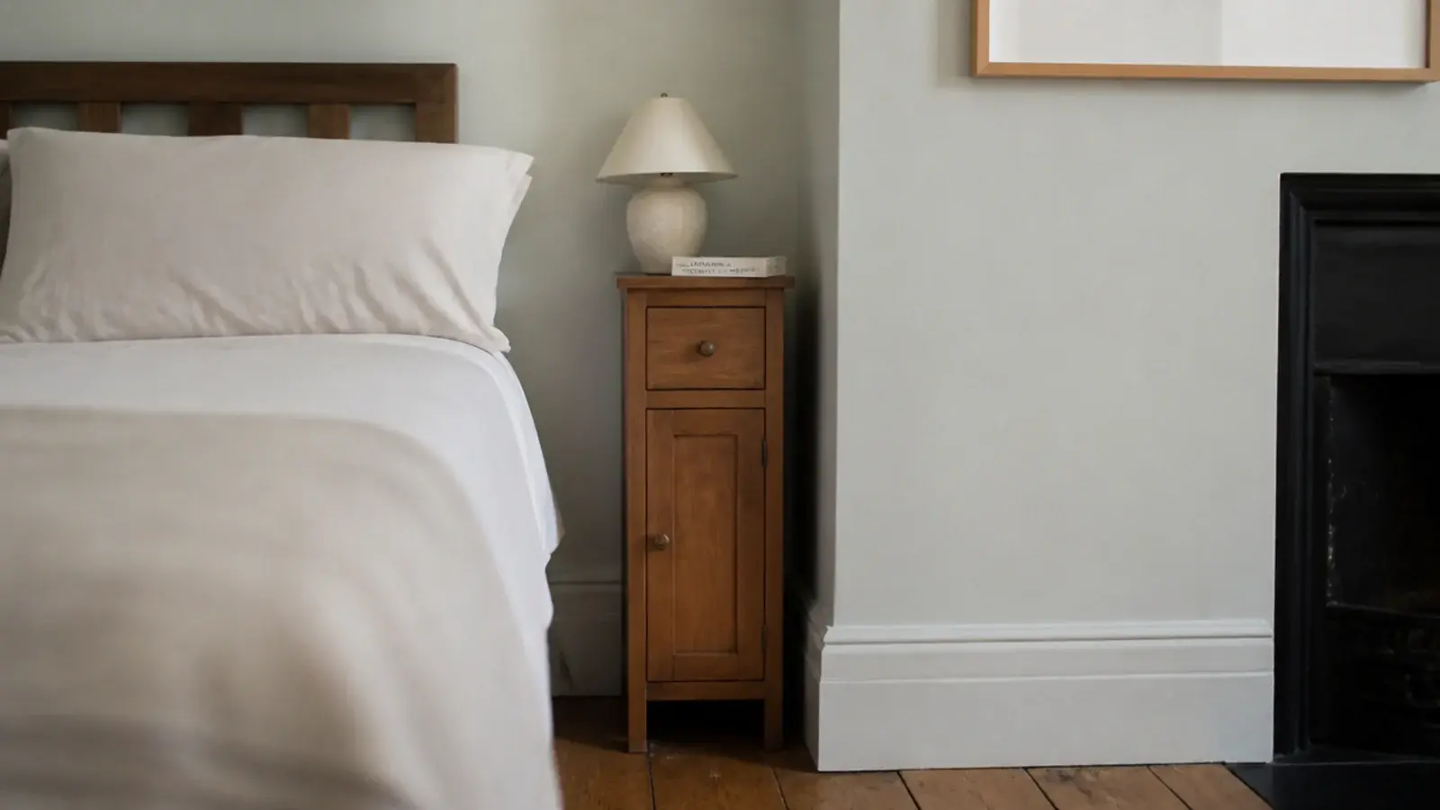 narrow bedside table fitted into a slim gap beside a linen dressed bed