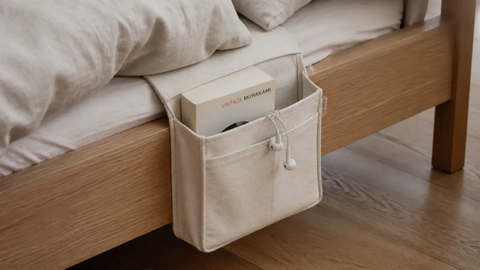 canvas caddy hooked over a wooden bed side rail holding a book