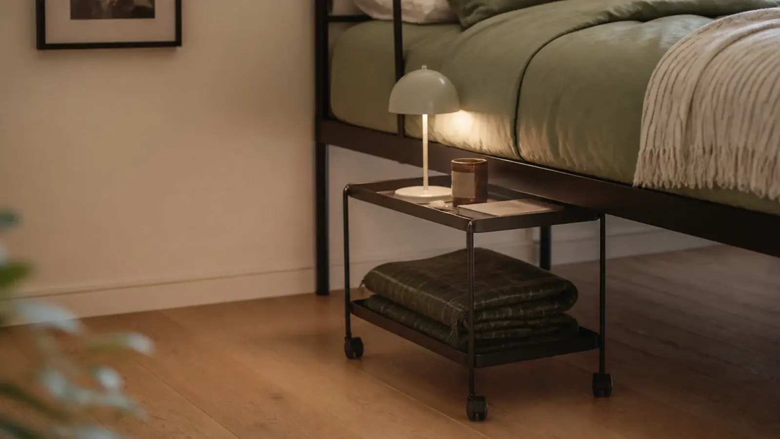 narrow two tier rolling cart pushed partly beneath a bed frame