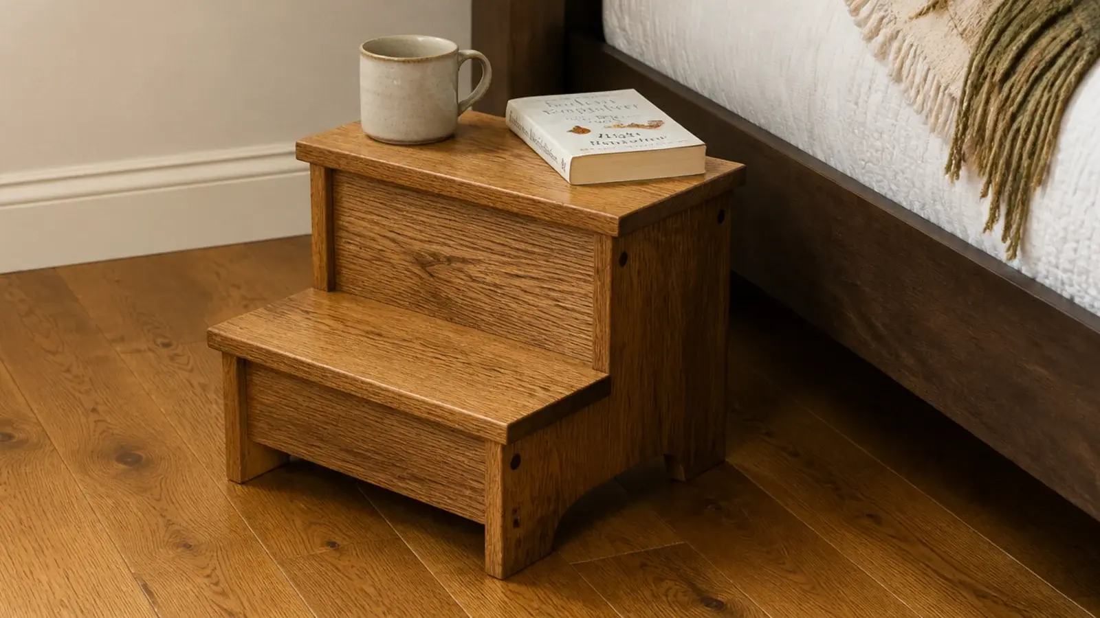 small wooden step stool used as a bedside table beside a high bed