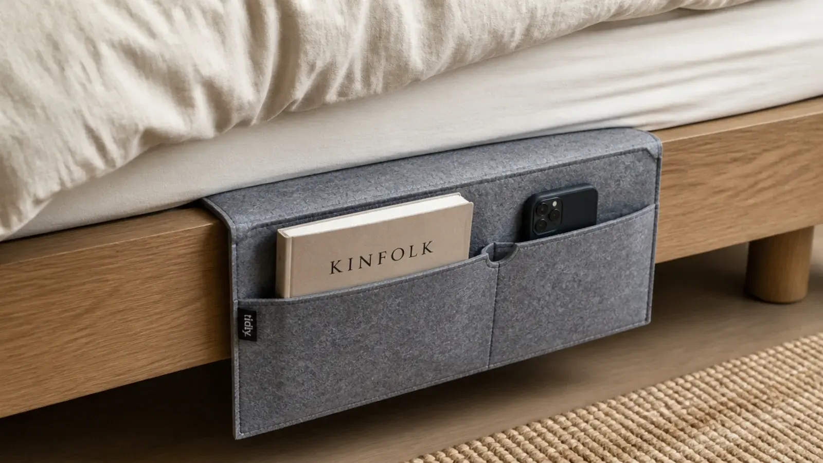 flat fabric caddy tucked beneath a mattress with pockets hanging down