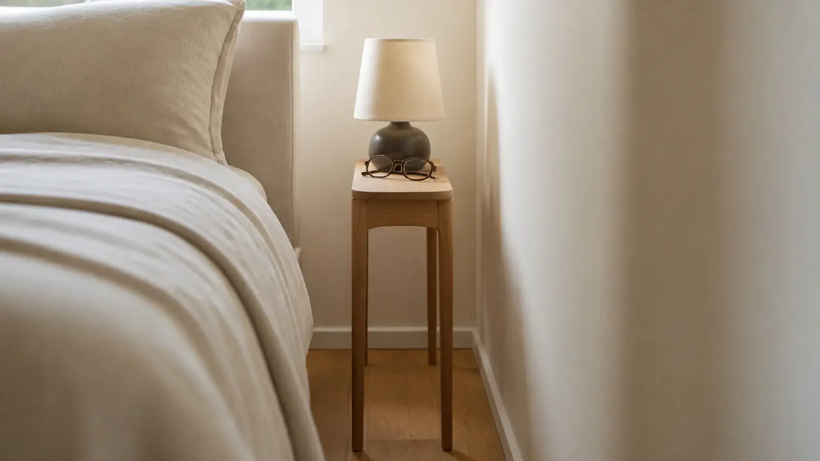 small bedside table ideas shown in a narrow gap beside a neatly made bed