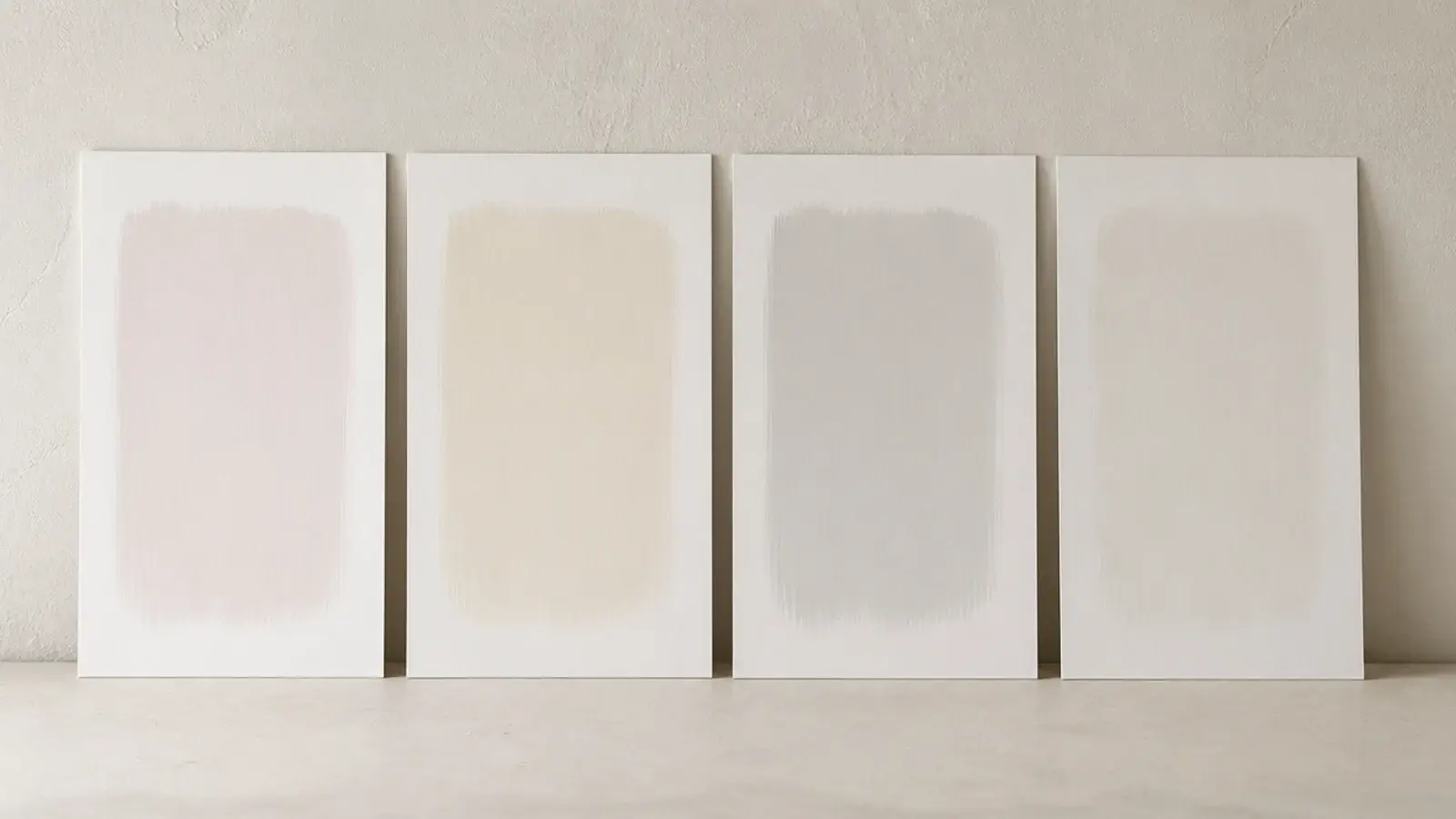 four painted white samples propped against a wall showing different undertones