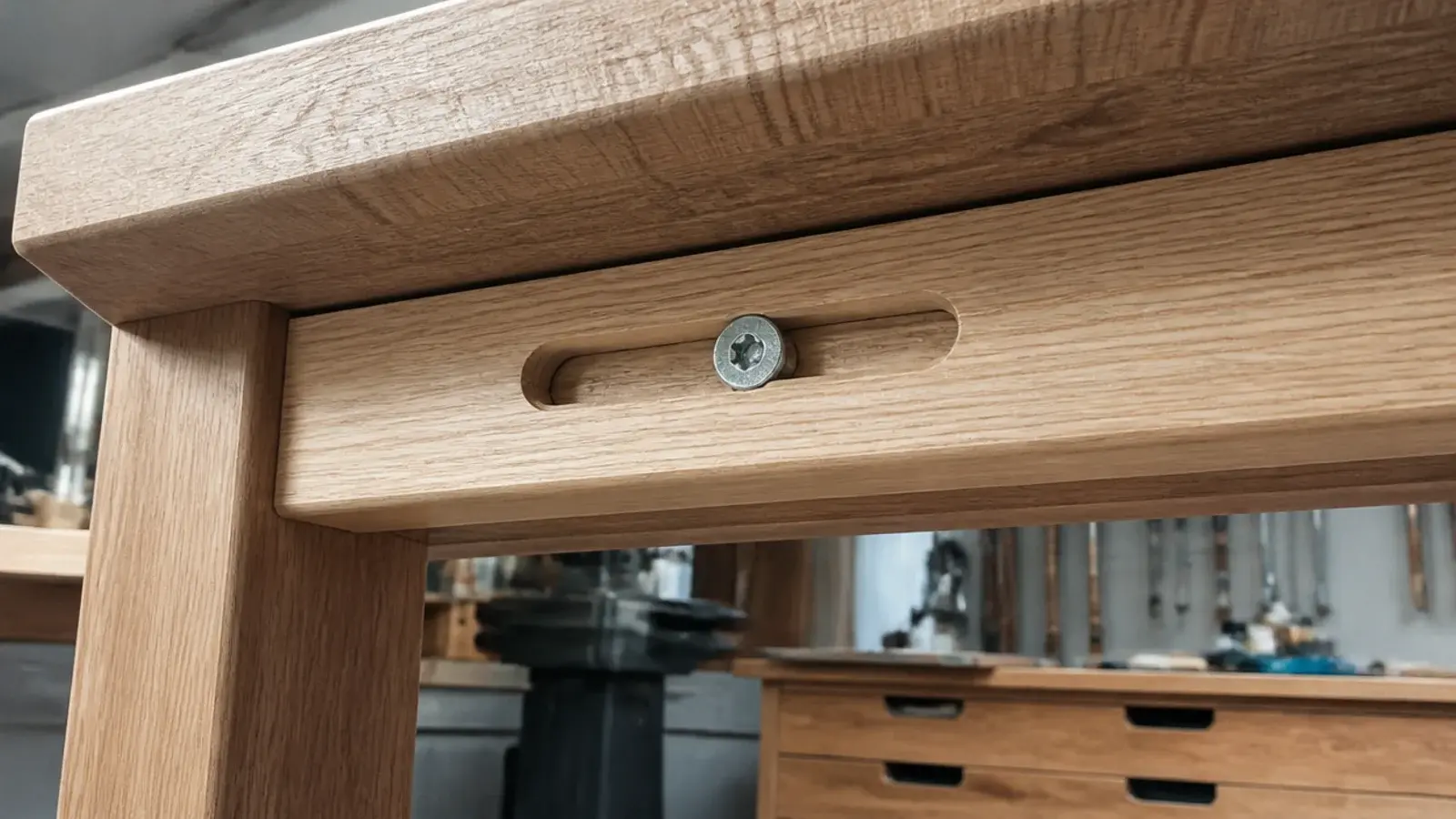 screw sitting in an elongated slot beneath a solid timber tabletop