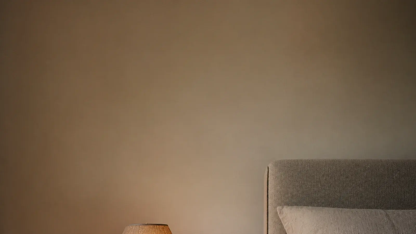 tall view of a wooden bedside table in oak with lamp and open book