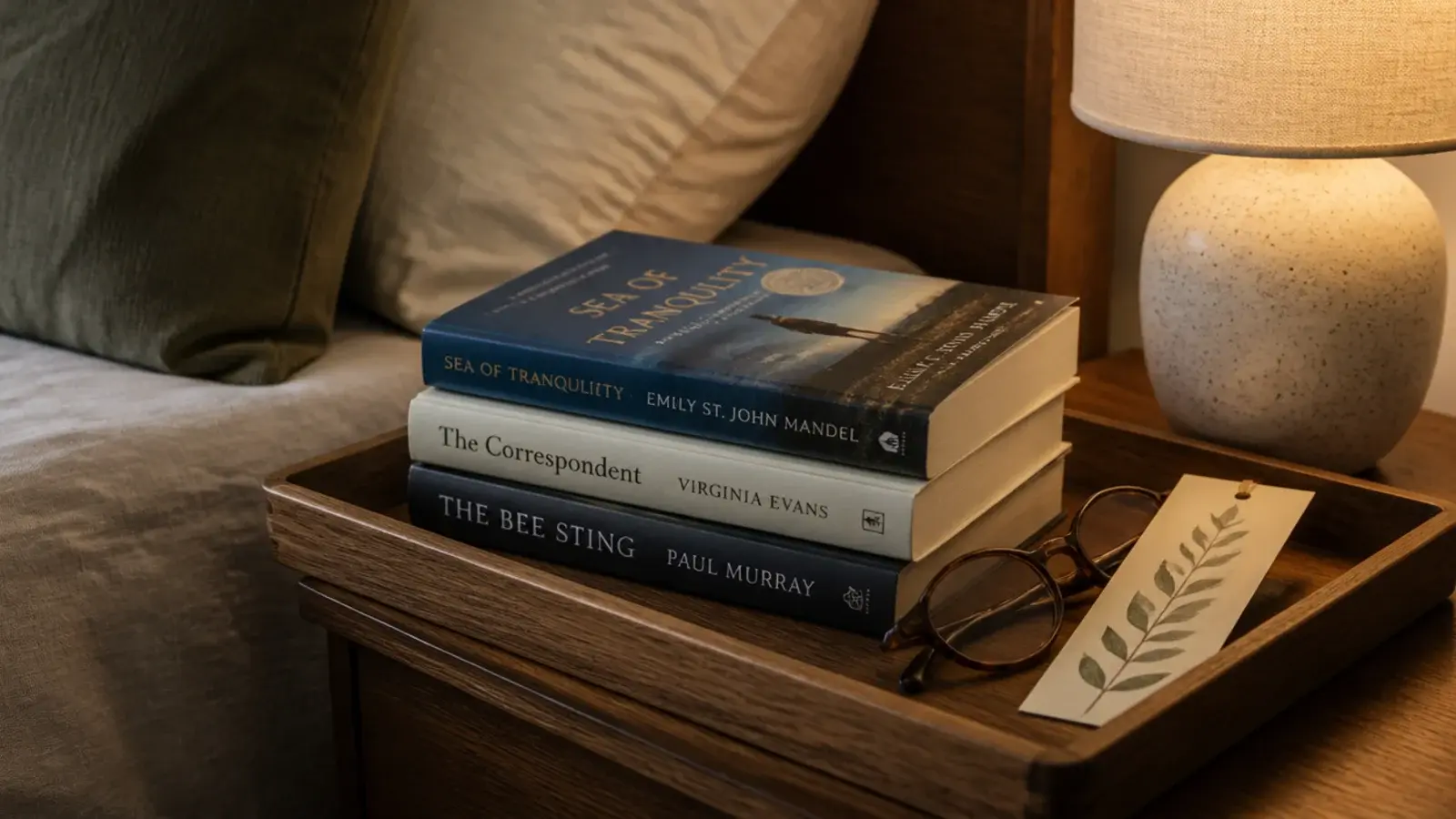 small wooden tray of current reads and glasses on a nightstand
