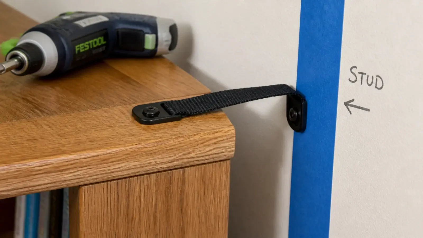 anti-tip strap fixed from a bookcase top rail into a wall stud