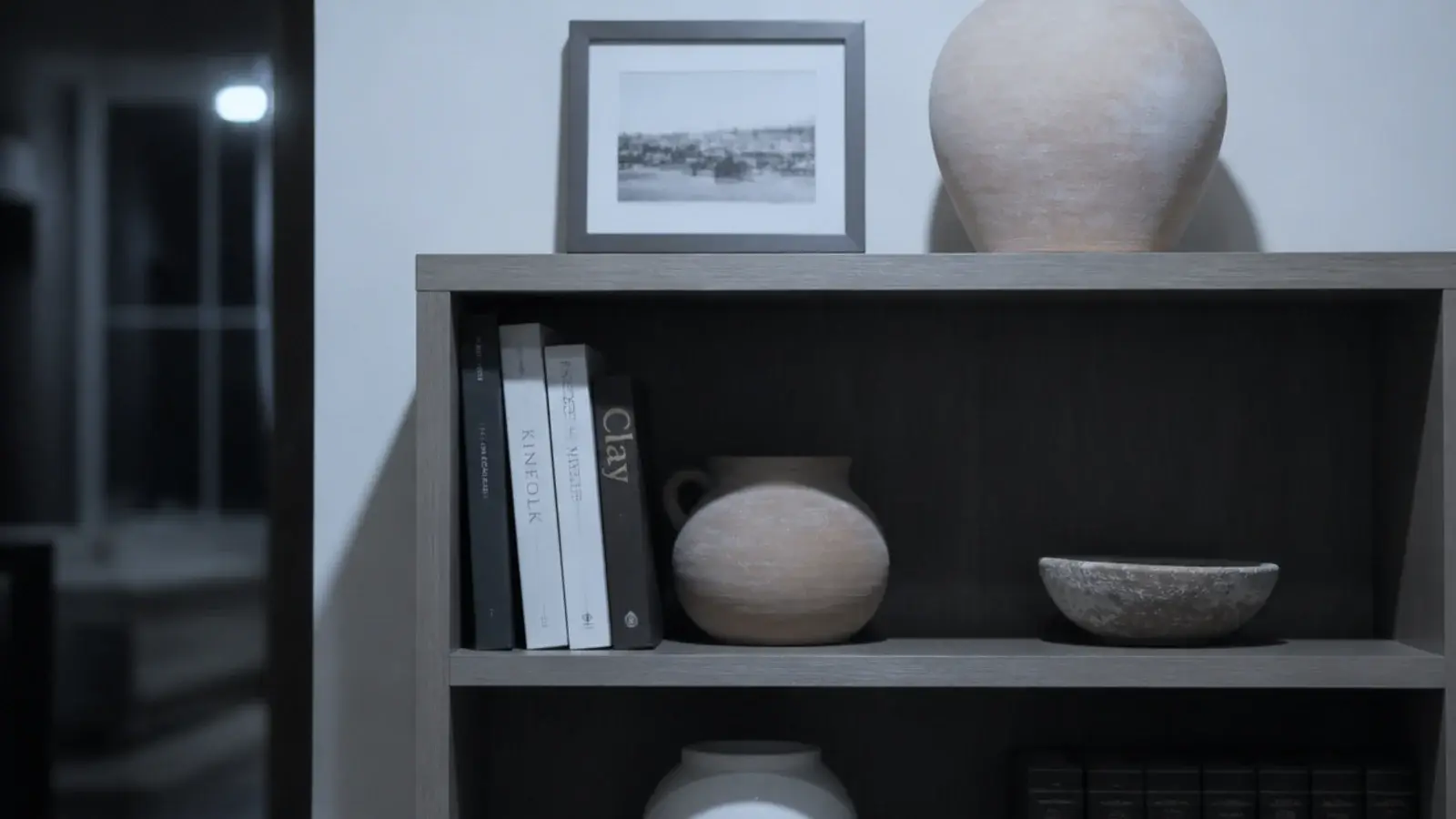 bookshelf under cool white light making oak and terracotta look gray