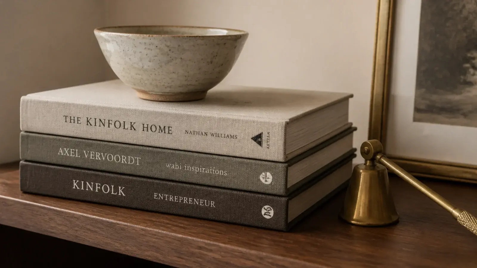 three hardbacks stacked flat lifting a small ceramic bowl on a shelf