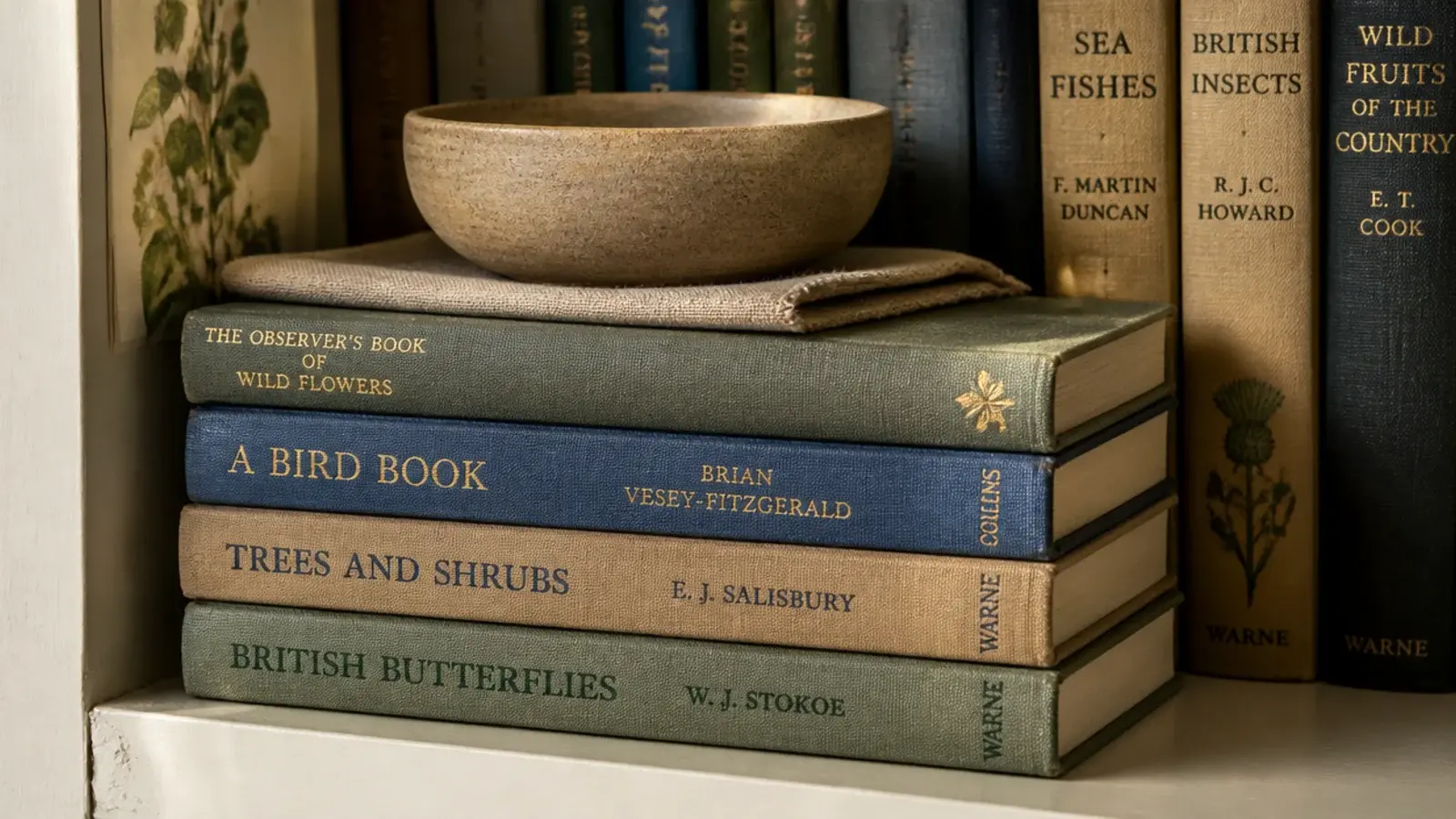 three hardbacks laid flat as a pedestal under a small clay bowl