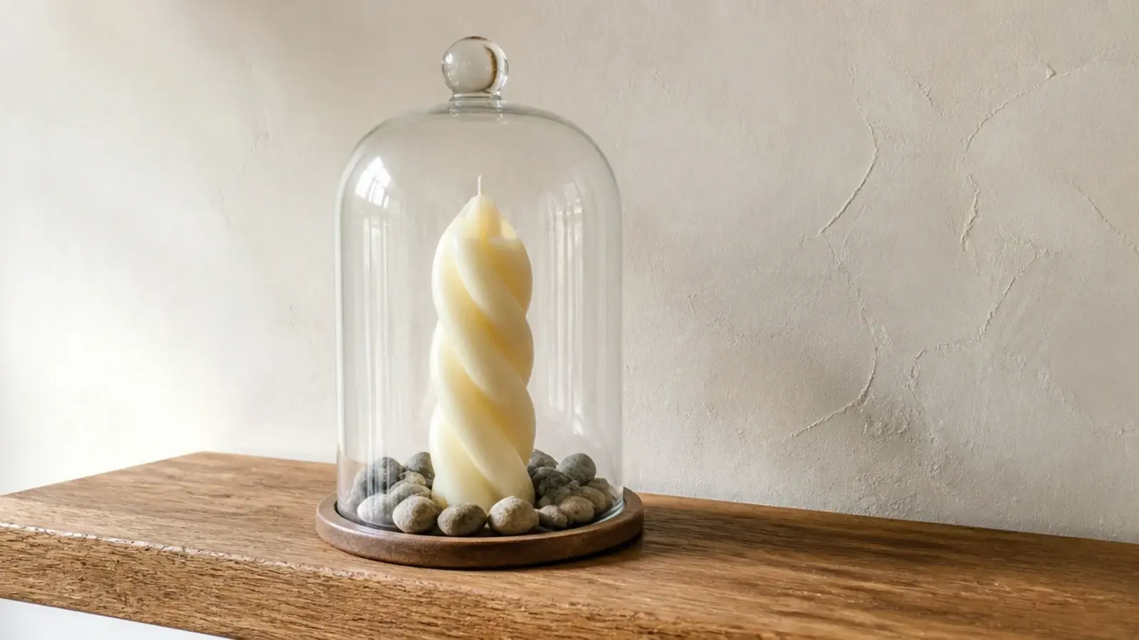 twisted sculptural candle displayed unlit under a glass cloche on shelving