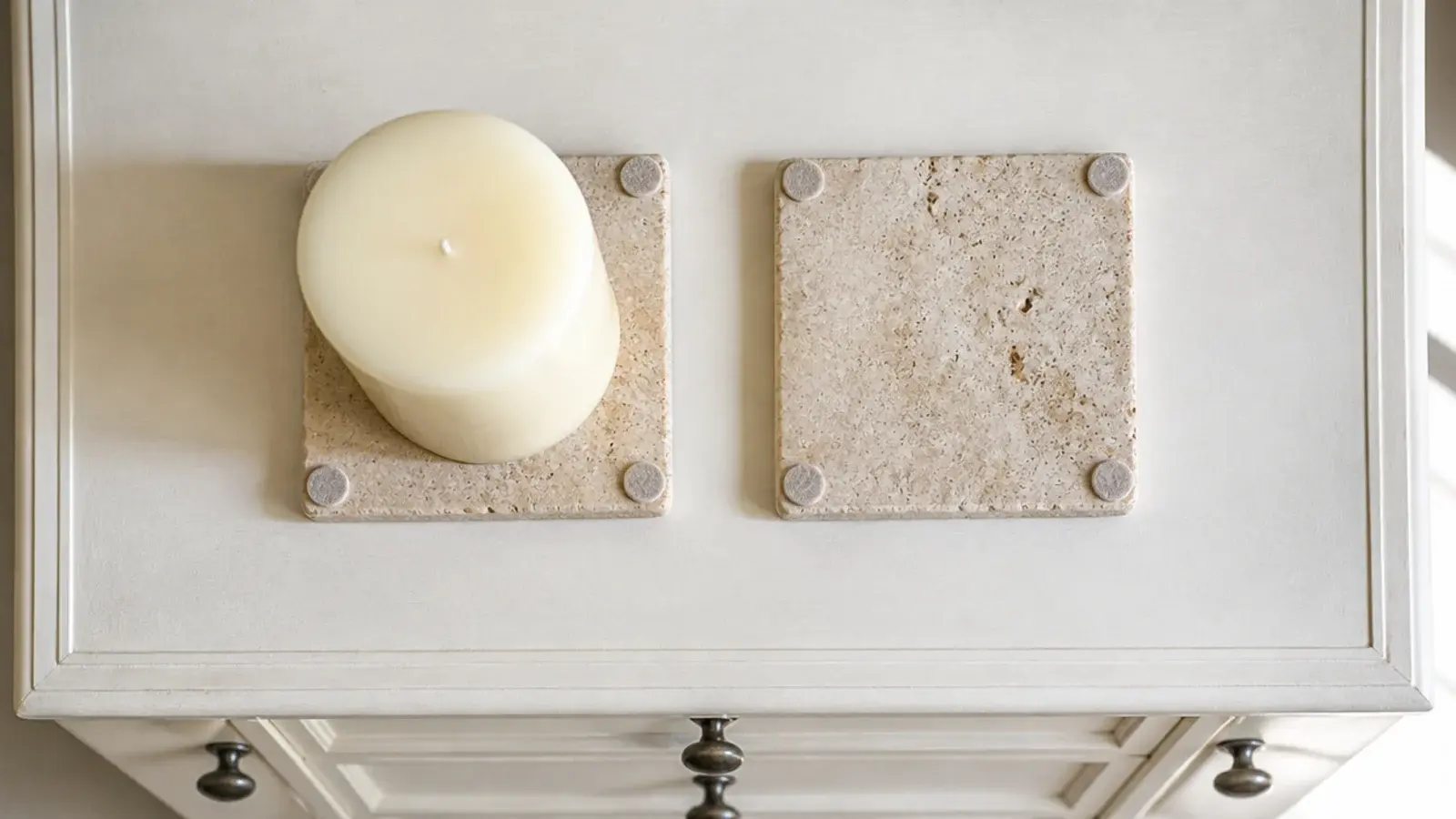 tile coaster with felt pads placed under a candle on painted furniture