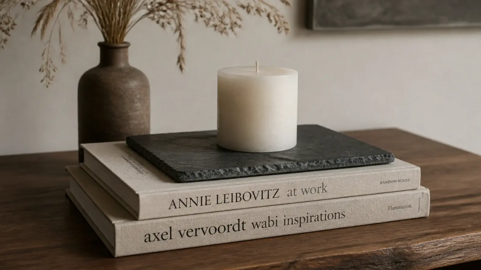 stacked art books topped with a slate tile holding a small pillar candle