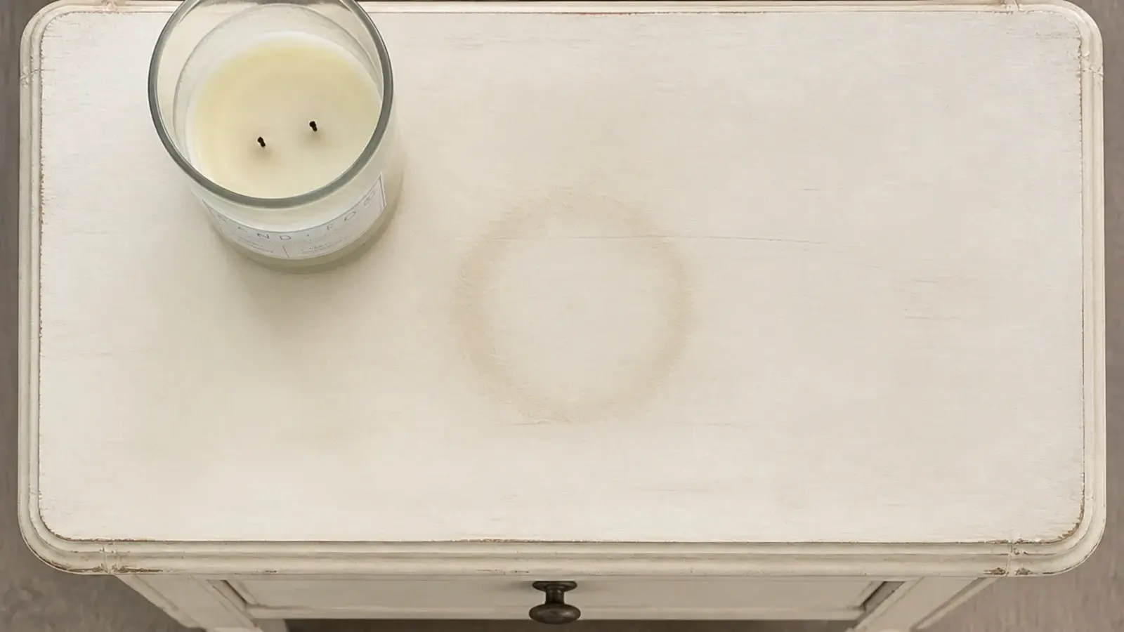 heat ring left on a painted side table where a jar candle stood