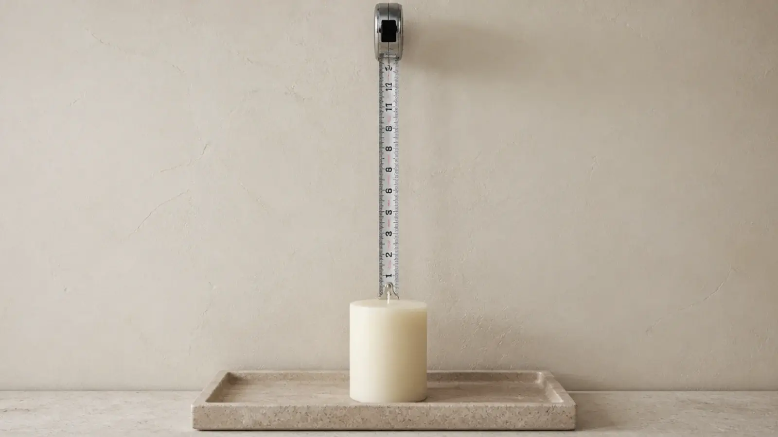 tape measure showing twelve inches of clearance above an unlit pillar candle