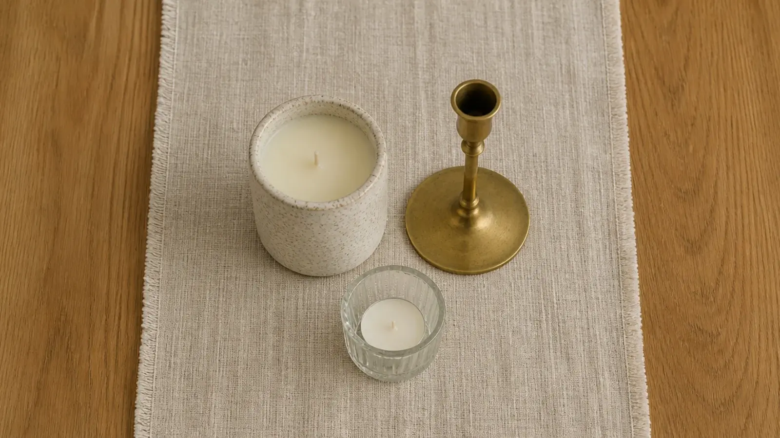 stoneware brass and glass candle vessels grouped on a linen runner