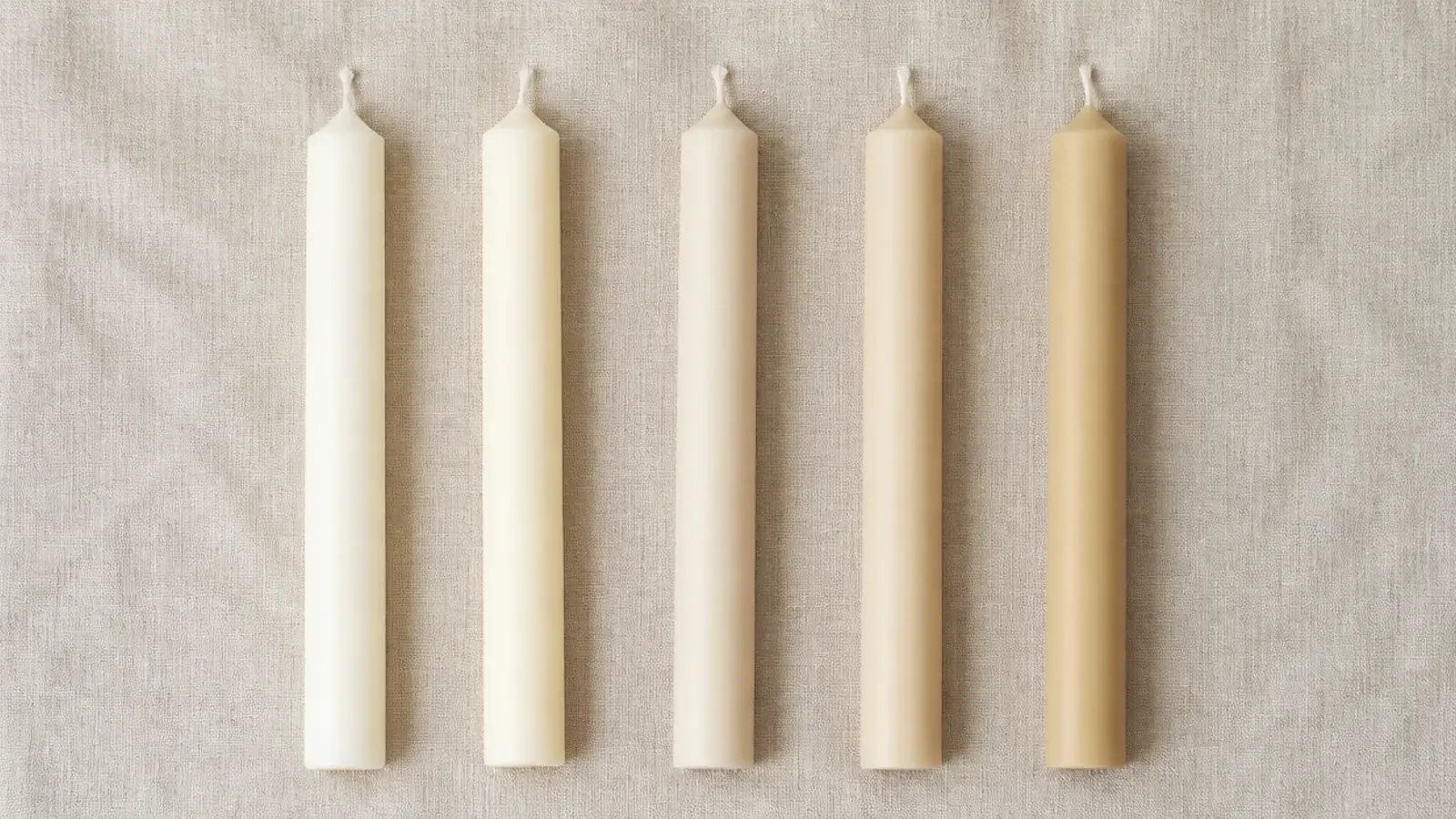 row of cream ivory and sand candles compared side by side on linen